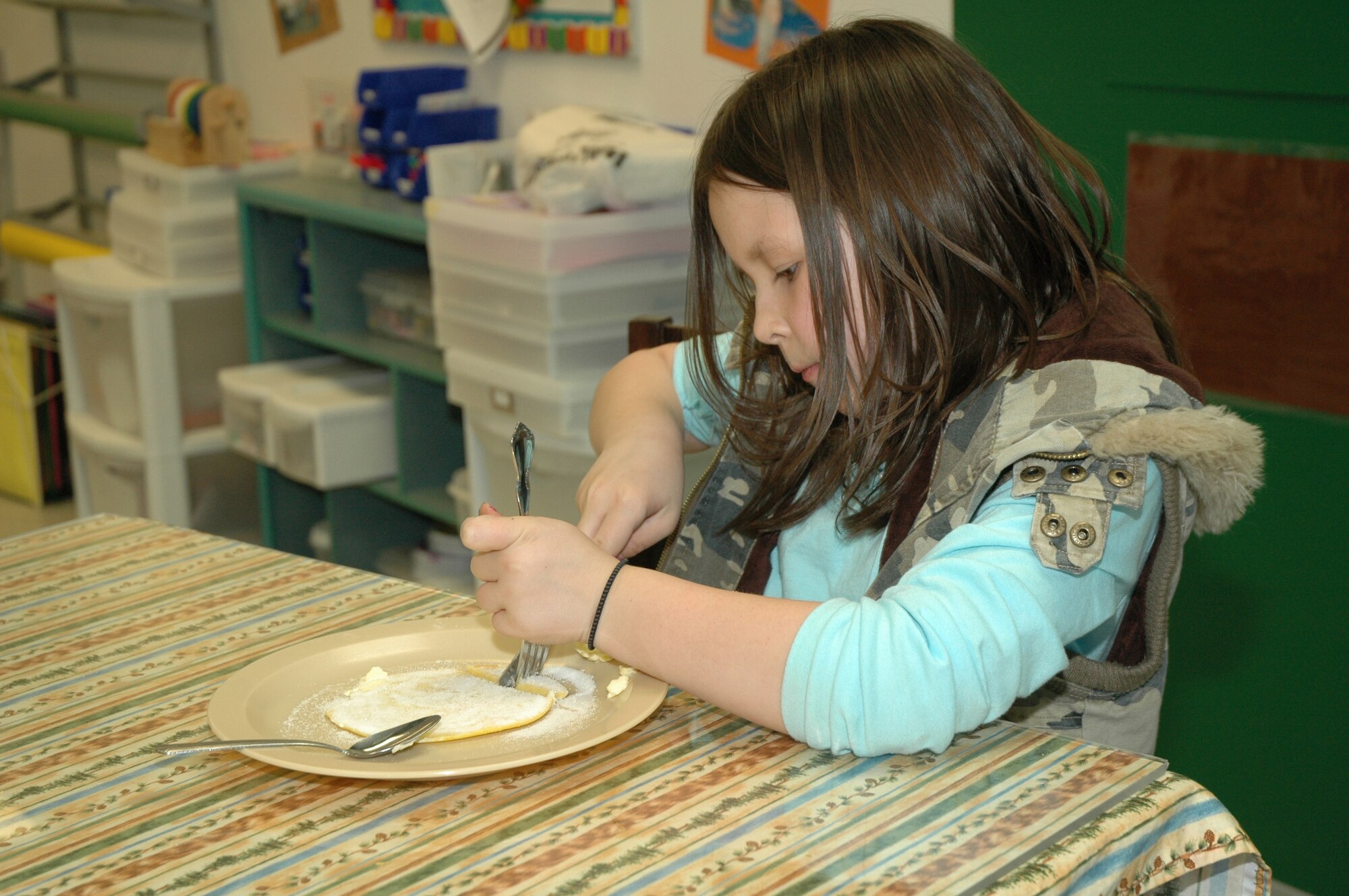 Little Warrior Terryn, 7, cuts her slapjack into bite sized pieces. The children who participated in the 4-H cooking class at the Youth Center March 7 also got to sample what they prepared.