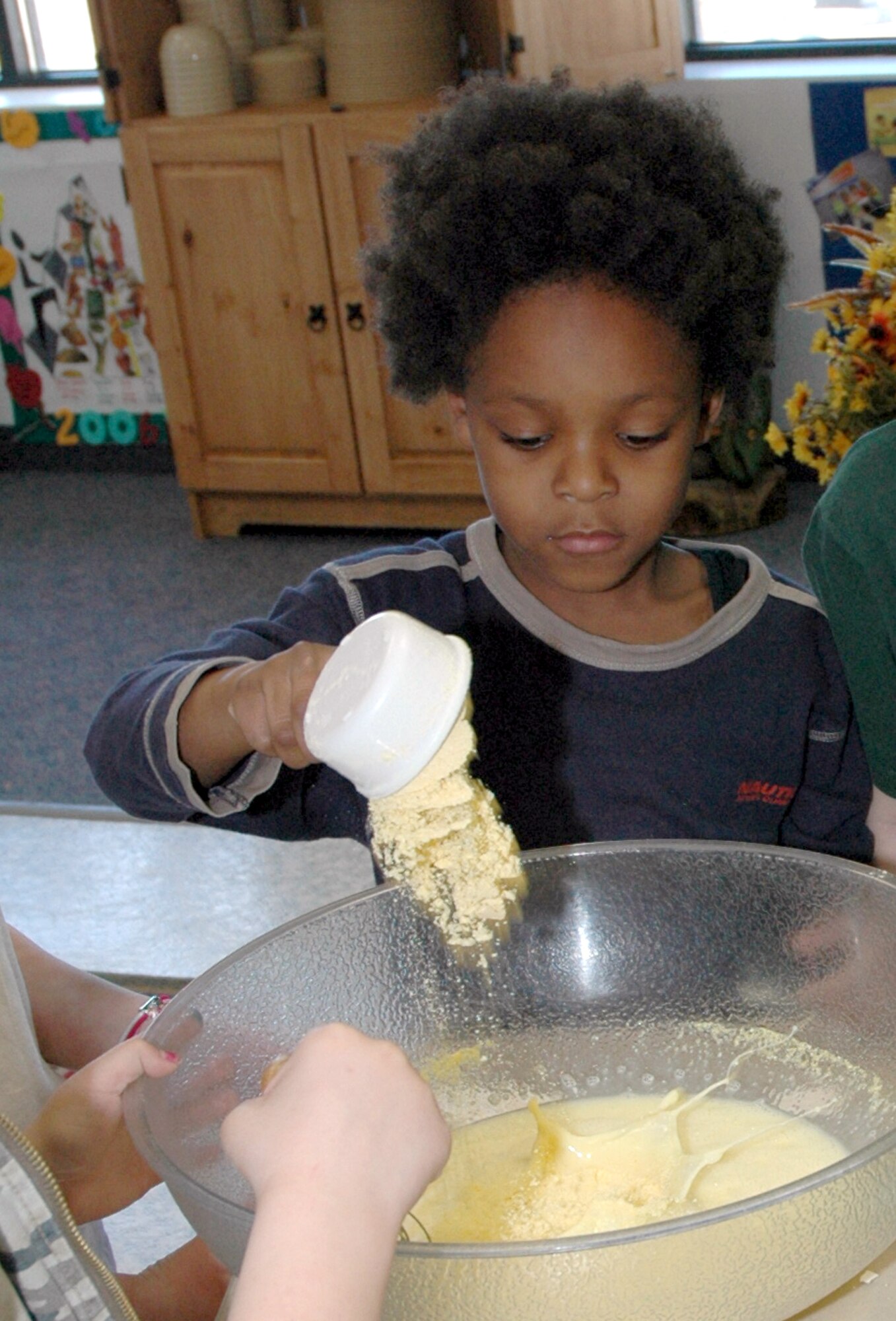 Little Warrior Montez, 6, adds cornmeal to the egg and milk mixture when it was his turn to add ingredients during the Youth Center's 4-h cooking class March 7.