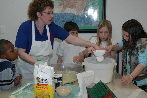 “Ms. Marjorie” Hahn is shown with Little Warriors (left to right) Jaylen, 6; Parker, 7; Reagan, 9; and Terryn, 8, during 4-H cooking class March 7 at the Youth Program Center. The children learned to make slapjacks.