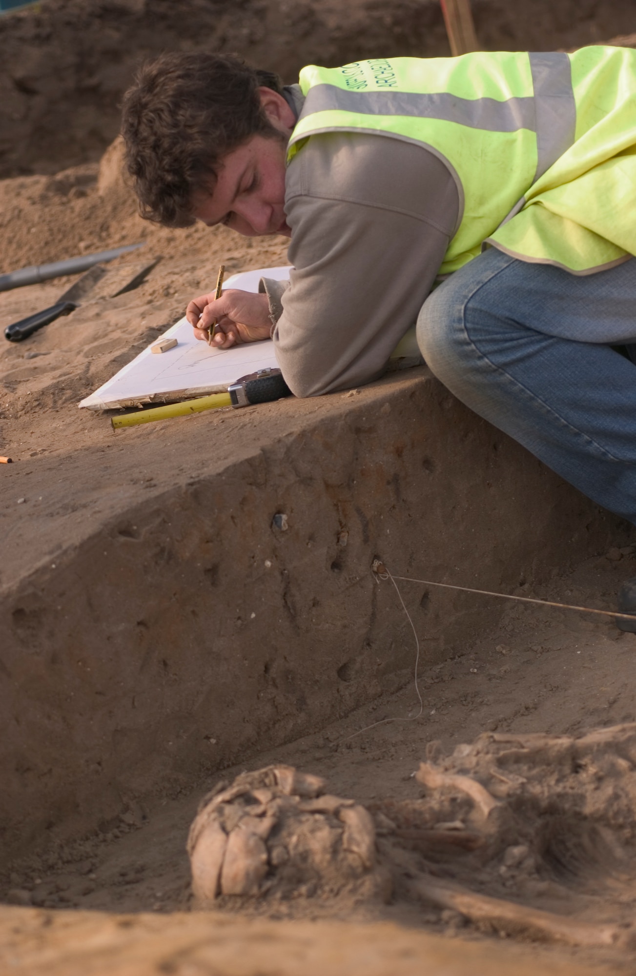 John Sims, an archeologist for Suffolk County Council, England, sketches a drawing March 14 of human remains prior to removing the bones for further study at the company's home office. The skeleton was found during an excavation of land where new base housing is planned to be constructed. It was estimated on site to be of 1st Century AD. Roman descent between 1,900 and 2,000 years old.  Mr. Sims has worked for Suffolk County Council for one and a half months, and the skeleton is his first significant find. (Air Force photo by Tech. Sgt. Tracy L. DeMarco)
