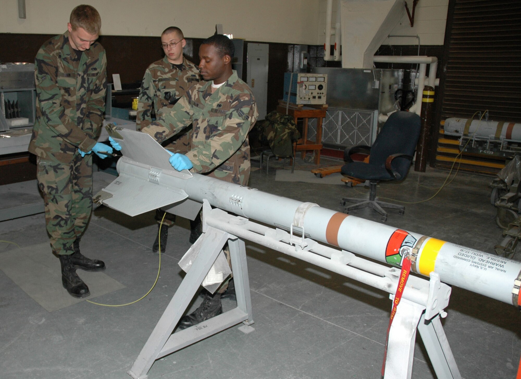 OSAN AIR BASE, Republic of Korea --  Airmen 1st Class Jesse Shaw and Theopolis Austin remove a fin from an AIM-9 missile while Airman 1st Class Cody Smith goes over the technical orders for the operation. (U.S. Air Force photo by Staff Sgt. Benjamin Rojek)