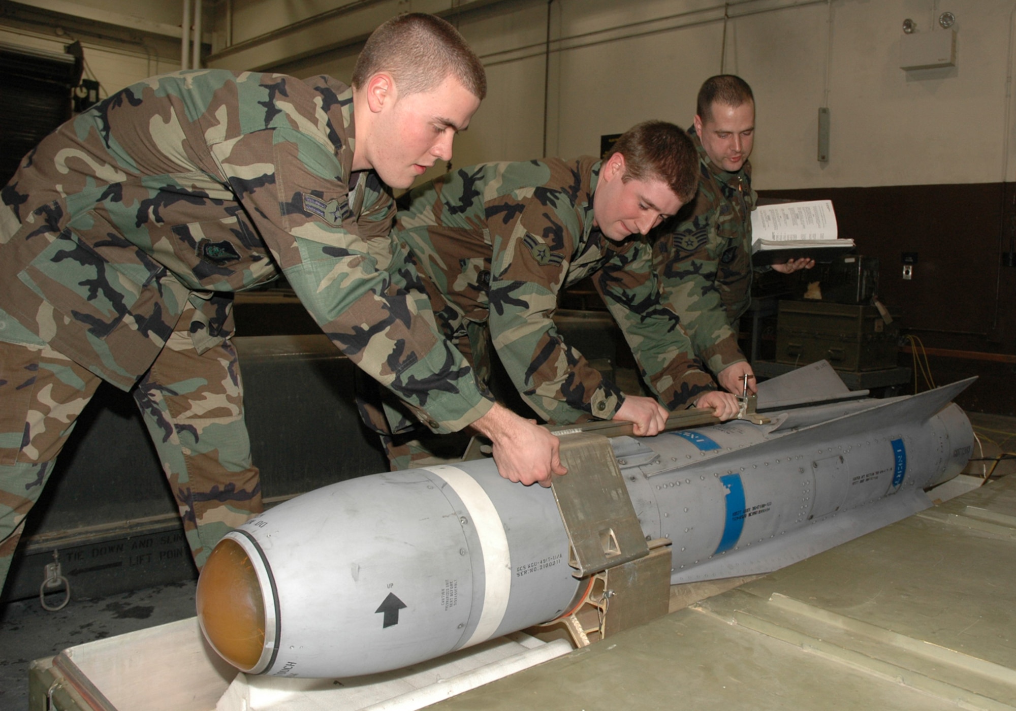 OSAN AIR BASE, Republic of Korea --  Airmen 1st Class Mark Stoia and Justin Simmons pull a Training Guided Missile-65D out of "the can" for an inspection as Staff Sgt. David Coughtry goes over technical orders. The three Airmen are with the 51st Munitions Squadron precision guided missiles section. (U.S. Air Force photo by Staff Sgt. Benjamin Rojek)