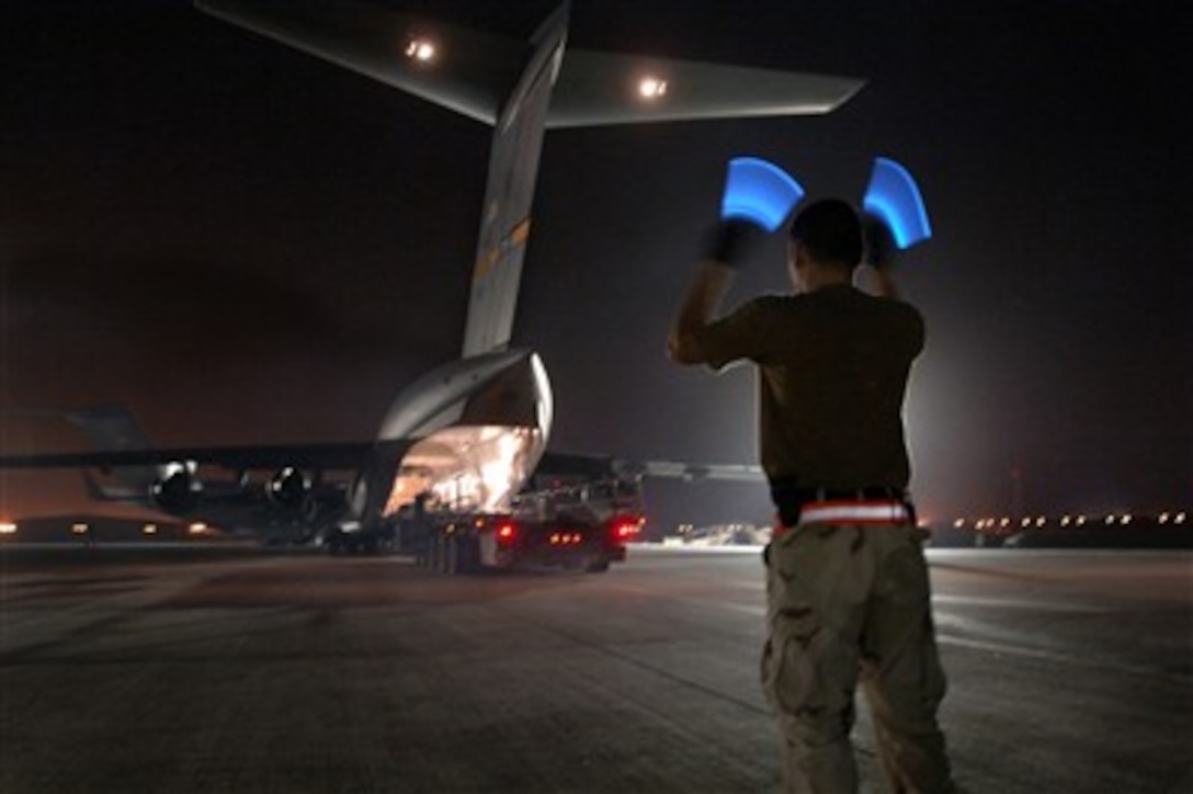 U.S. Air Force Airman 1st Class Arnold Pe'a directs the driver of an aircraft loader after loading pallets of bombs onto a C-17 Globemaster III aircraft in Southwest Asia on March 6, 2007.  Aerial porters assigned to the 8th Expeditionary Air Mobility Squadron are handling approximately 2.1 million pounds of cargo per week.  