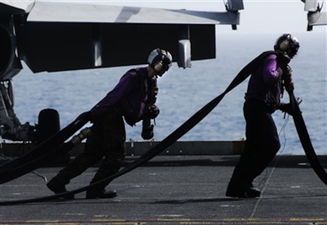 U.S. Navy sailors from the air department's flight deck aircraft handling division heave fuel hoses out to refuel aircraft aboard the aircraft carrier USS John C. Stennis (CVN 74) as the ship operates in the Arabian Sea on March 8, 2007.  