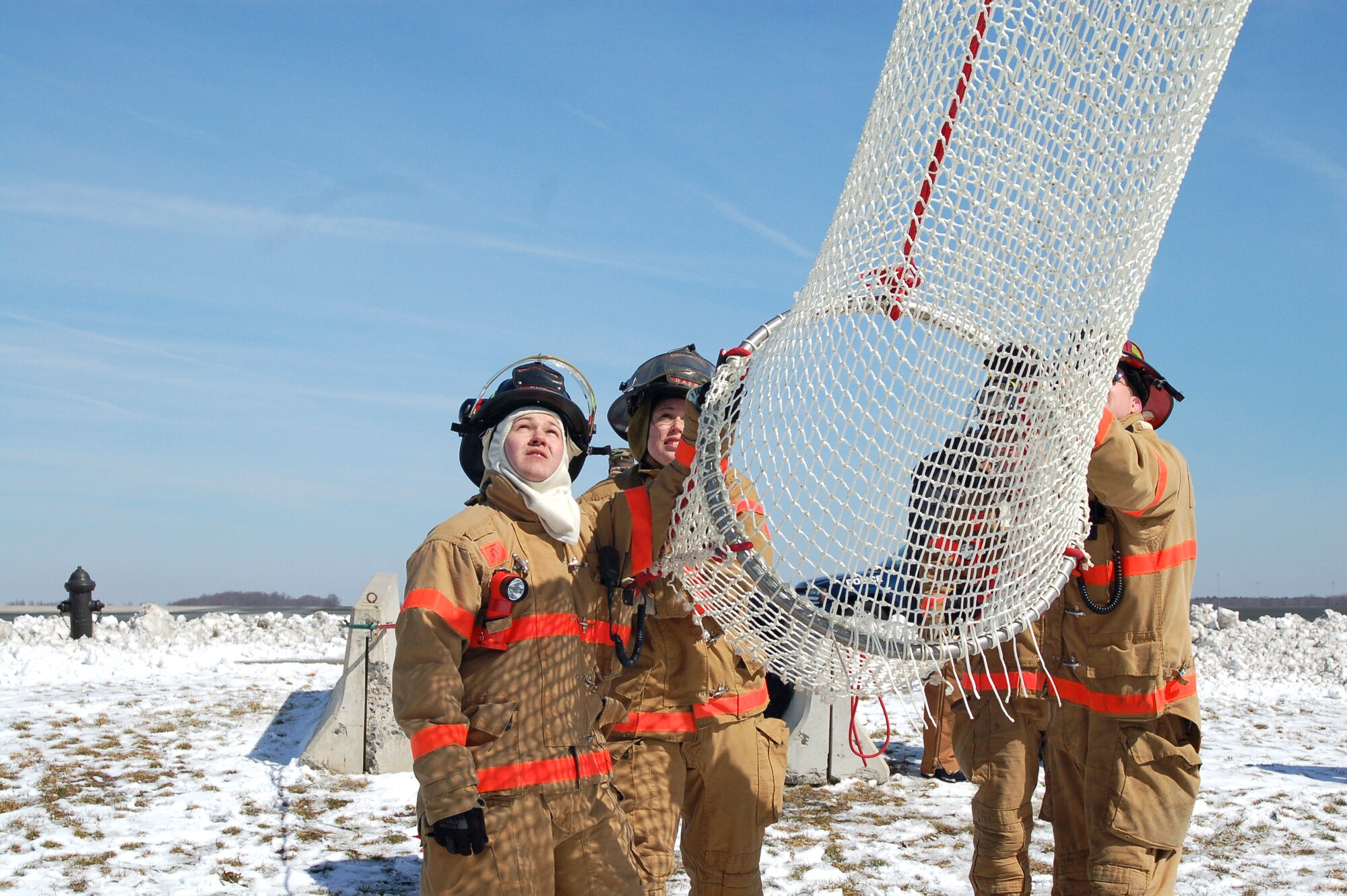 Airman Kyle Herron (from left), Airman 1st Class Darliska Blessing, Jeffrey McCombs and Tom Peers wait to assist a Dover Air Force Base, Del., tower controller descending in a Baker Life Chute from the control tower March 8 during a fire drill.  The life chute was installed on the tower's catwalk and is designed to allow controllers a safe descent to the ground level in the event of an emergency.  The firefighters are from the 436th Civil Engineer Squadron.  (U.S. Air Force photo/Tech. Sgt. Kevin Wallace) 