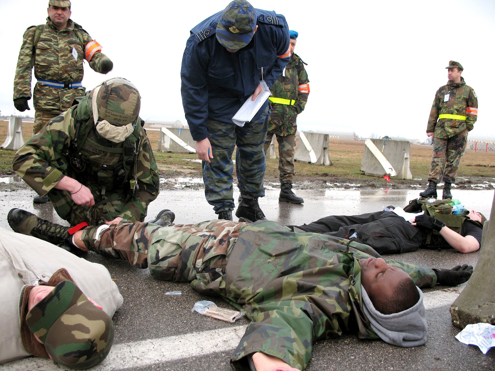 Senior Airman Patrick Wilsey (left) performs first aid on a role-playing injured demonstrator after a simulated bomb explosion. Greek NATO Inspector Capt. Panousis Dimitris verifies Airman Wilsey is performing the correct procedures. Airman Wilsey is with the 31st Security Forces Squadron. (U.S. Air Force photo/Airman 1st Class Justin Goodrich)