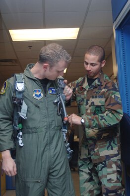 Staff Sgt. James Chase, 50th Flying Training Squadron Life Support, helps 1st Lt. Johnny Koegel, 50th FTS, tighten the straps on his parachute before going out to a flight.