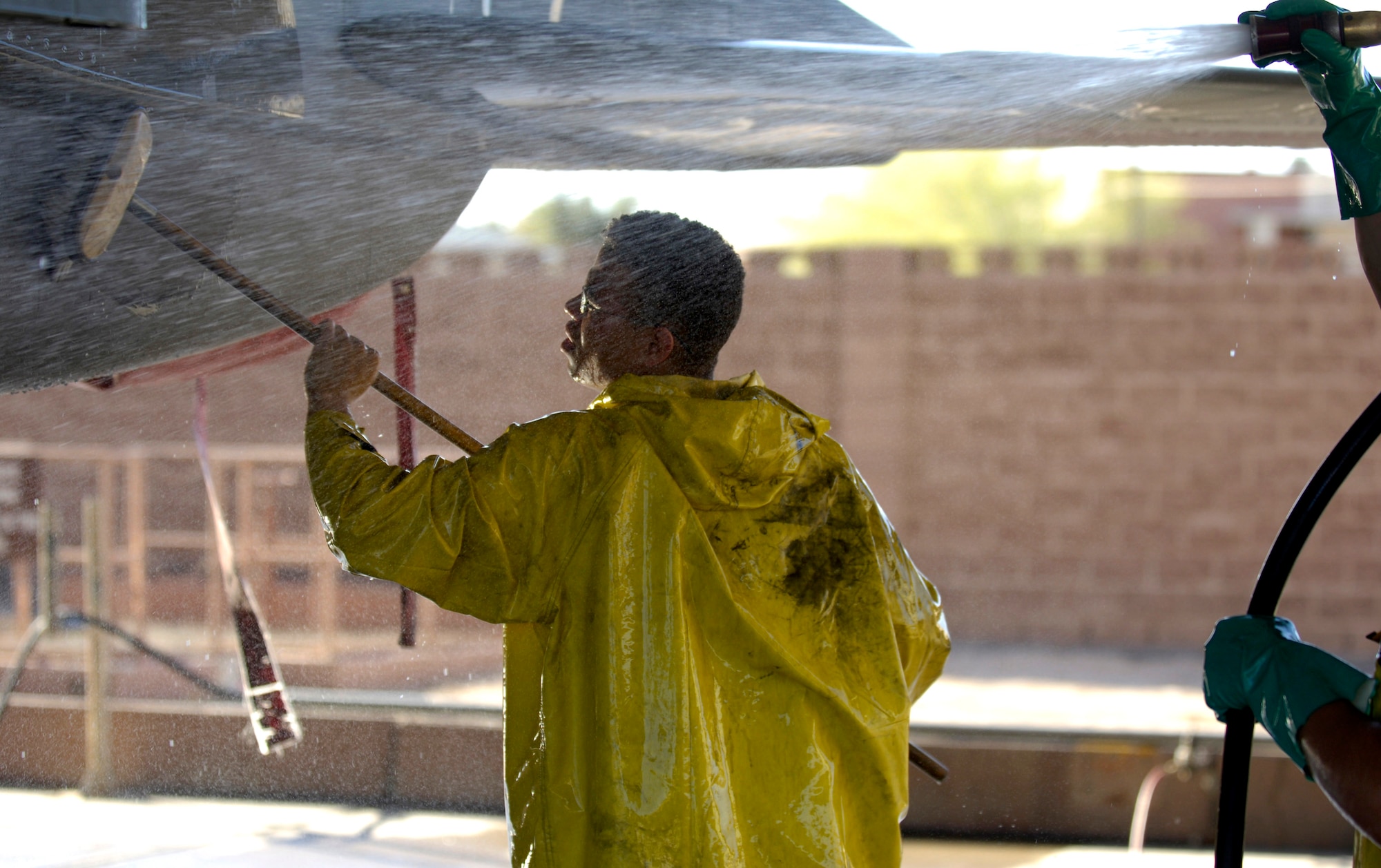 Airman 1st Class Brian Roy scrubs a panel on an F-15E Strike Eagle while Senior Airman Edward Taylor works the hose during a 120-day periodic cleaning March 15 at Nellis Air Force Base, Nev.  The complete F-15 cleaning process takes approximately four hours with a crew of three.  Airman Roy, a weapons specialist, and Airman Taylor, a crew chief, are both assigned to the 57th Aircraft Maintenance Squadron at Nellis.  (U.S. Air Force photo/Master Sgt. Kevin J. Gruenwald)