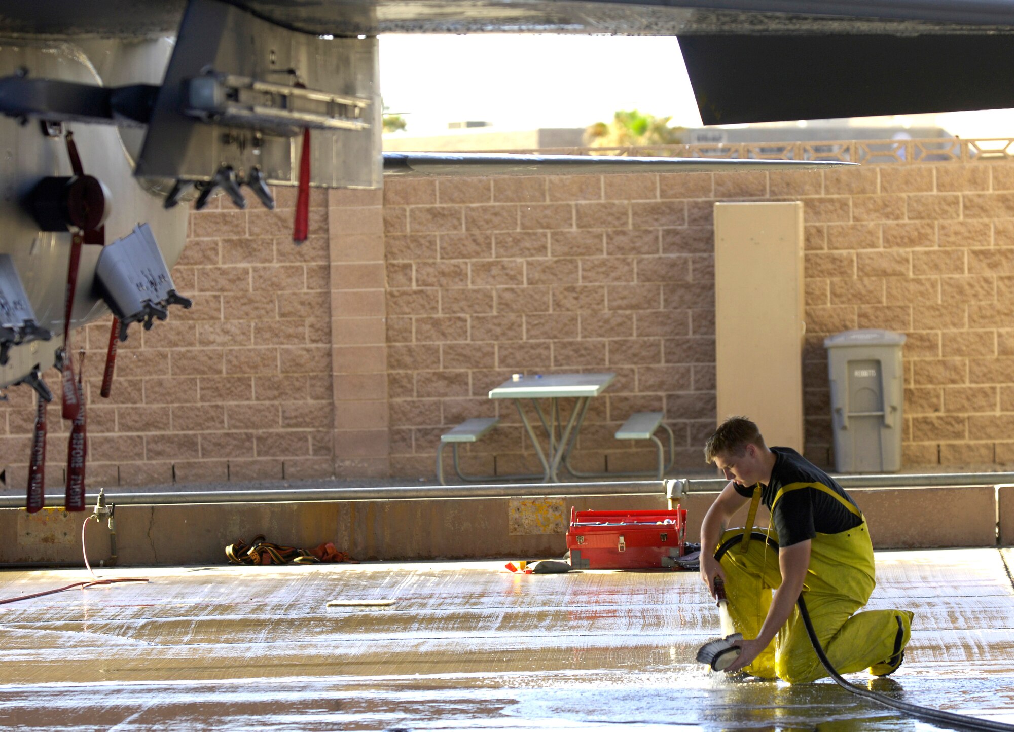 Airman 1st Class Dylan Edson rinses his brush while washing an F-15E Strike Eagle during a 120-day periodic cleaning March 15 at Nellis Air Force Base, Nev.  The complete F-15 cleaning process takes approximately four hours with a crew of three.  Airman Edson is an avionics specialist assigned to the 57th Aircraft Maintenance Squadron at Nellis.  (U.S. Air Force photo/Master Sgt. Kevin J. Gruenwald)