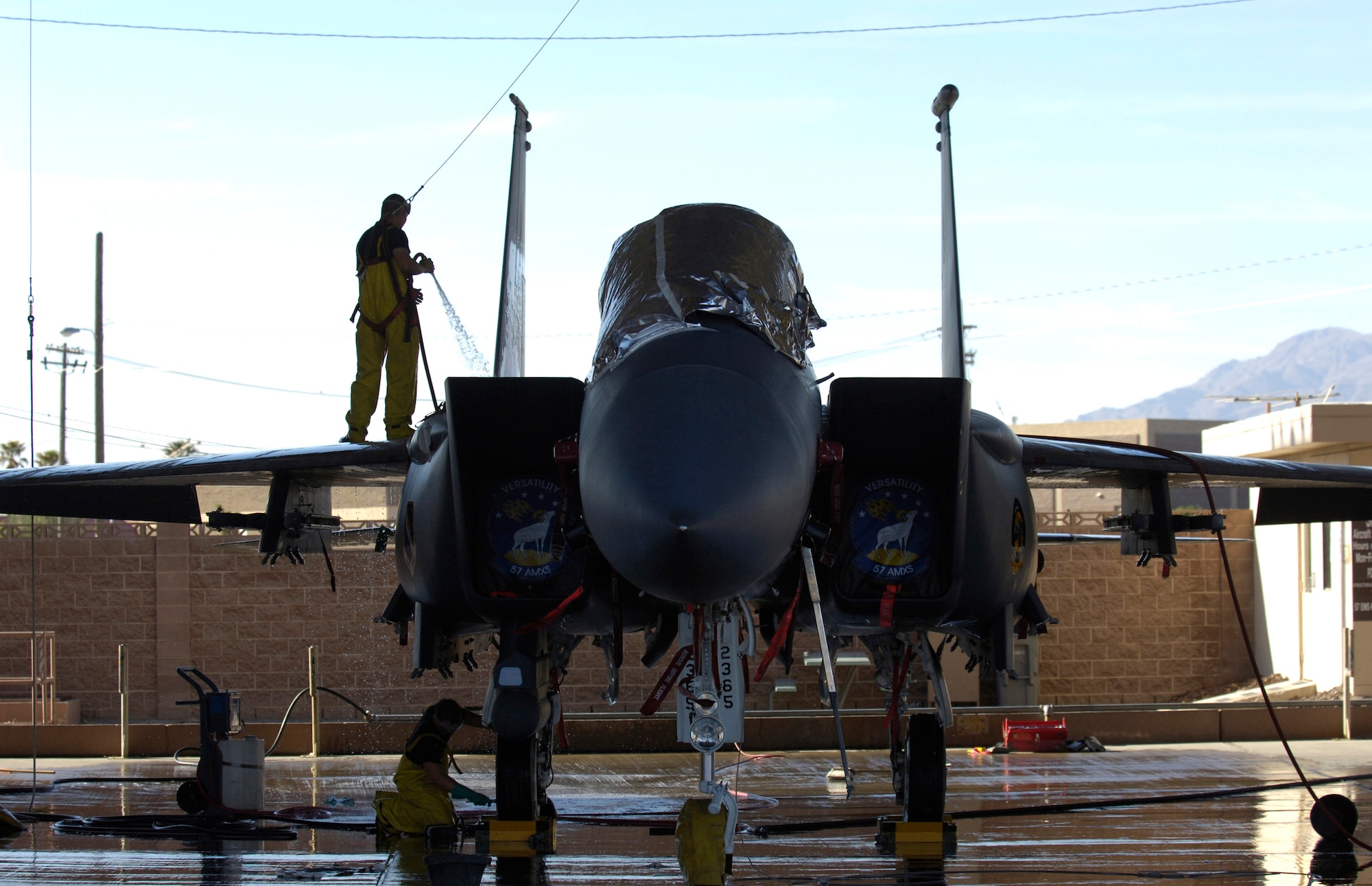 Senior Airman Edward Taylor (on aircraft) and Airman 1st Class Dylan Edson wash an F-15E Strike Eagle during a 120-day periodic cleaning March 15 at Nellis Air Force Base, Nev.  The complete F-15 cleaning process takes approximately four hours with a crew of three.  Airman Taylor, a crew chief, and Airman Edson, an avionics specialist, are both assigned to the 57th Aircraft Maintenance Squadron at Nellis.  (U.S. Air Force photo/Master Sgt. Kevin J. Gruenwald)