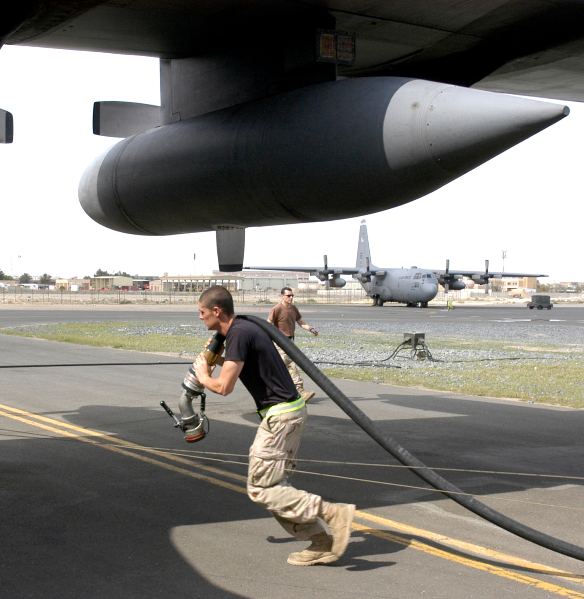 A member of the 386th Expeditionary Logistics Readiness Squadron at a forward-deployed location rushes to re-fuel a C-130 Hercules before it continues on an airlift mission. Airmen from the 386 ELRS perform a vital mission on a daily basis, pumping aproximately 100,000 to 150,000 