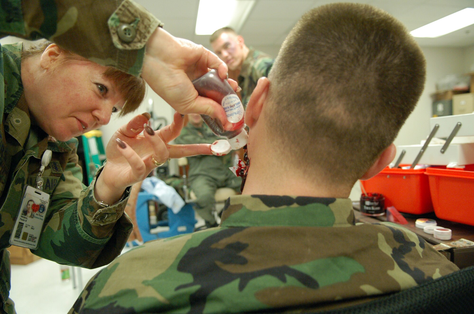 LAUGHLIN AIR FORCE BASE, Texas -- Maj. Paula Winters, Family Medicine Flight commander, applies fake blood to the neck of 2nd Lt. Raymond Paterson, who has simulated shards of glass lodged in his flesh.  (U.S. Air Force photo by Staff Sgt. Austin M. May)