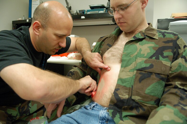 LAUGHLIN AIR FORCE BASE, Texas -- Capt. John Weaver, 47th Medical Group readiness officer, begins preparing the site where a soda can would be imbedded in the stomach of 2nd Lt. Todd Mickel for an exercise involving a tornado.  (U.S. Air Force photo by Staff Sgt. Austin M. May)