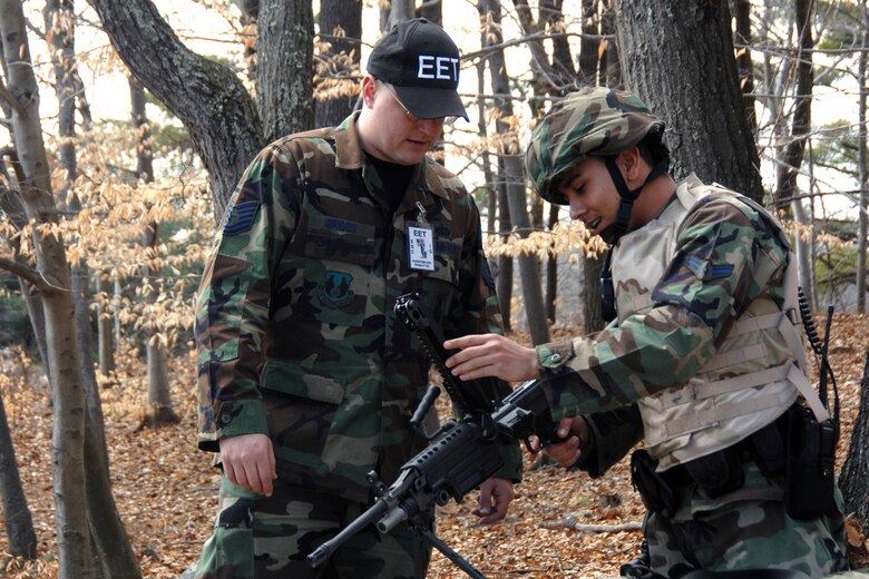 Airman 1st Class Hector Girola, 66 SFS patrolman, answers questions posed by Exercise Evaluation Team member Tech. Sgt. Wayne Griggs about the fully automatic M-249 rifle during the Hanscom March Base Readiness Exercise.  (US Air Force Photo by Linda LaBonte Britt)
