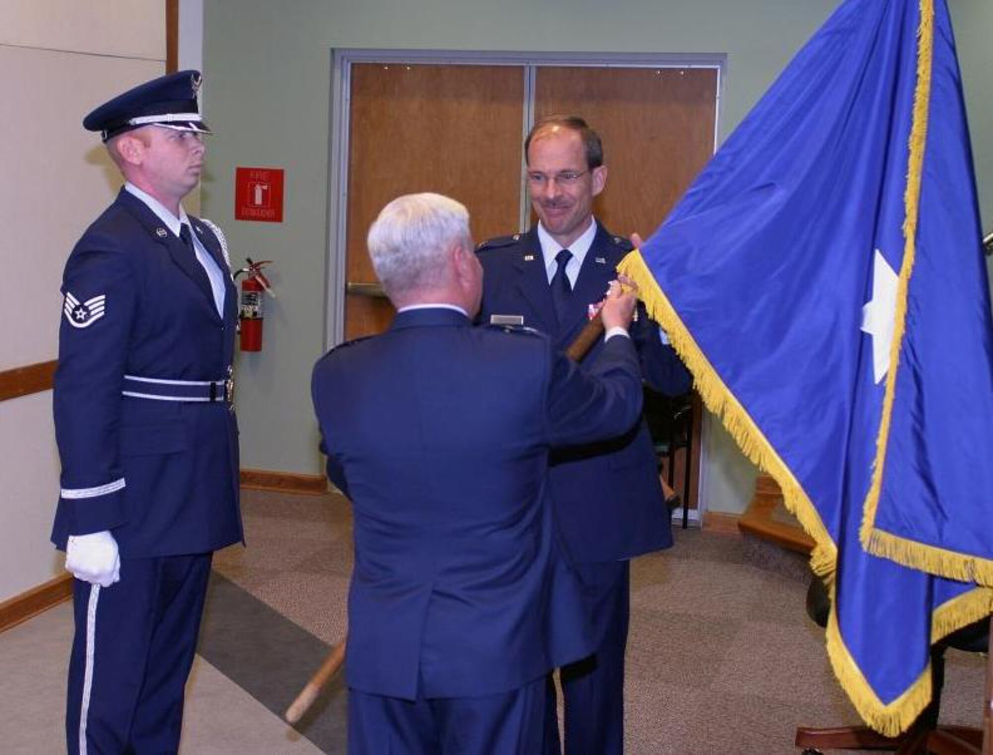 Newly promoted Brig. Gen. Jon R. Shasteen accepts a general’s flag from Maj. Gen. Allan R. Poulin, the officiating officer at General Shasteen’s promotion ceremony. Staff Sgt. Ryan Ayers, 482nd Fighter Wing Honor Guard, stands left of the generals. (U.S. Air Force photo/Tech. Sgt. Paul Dean)