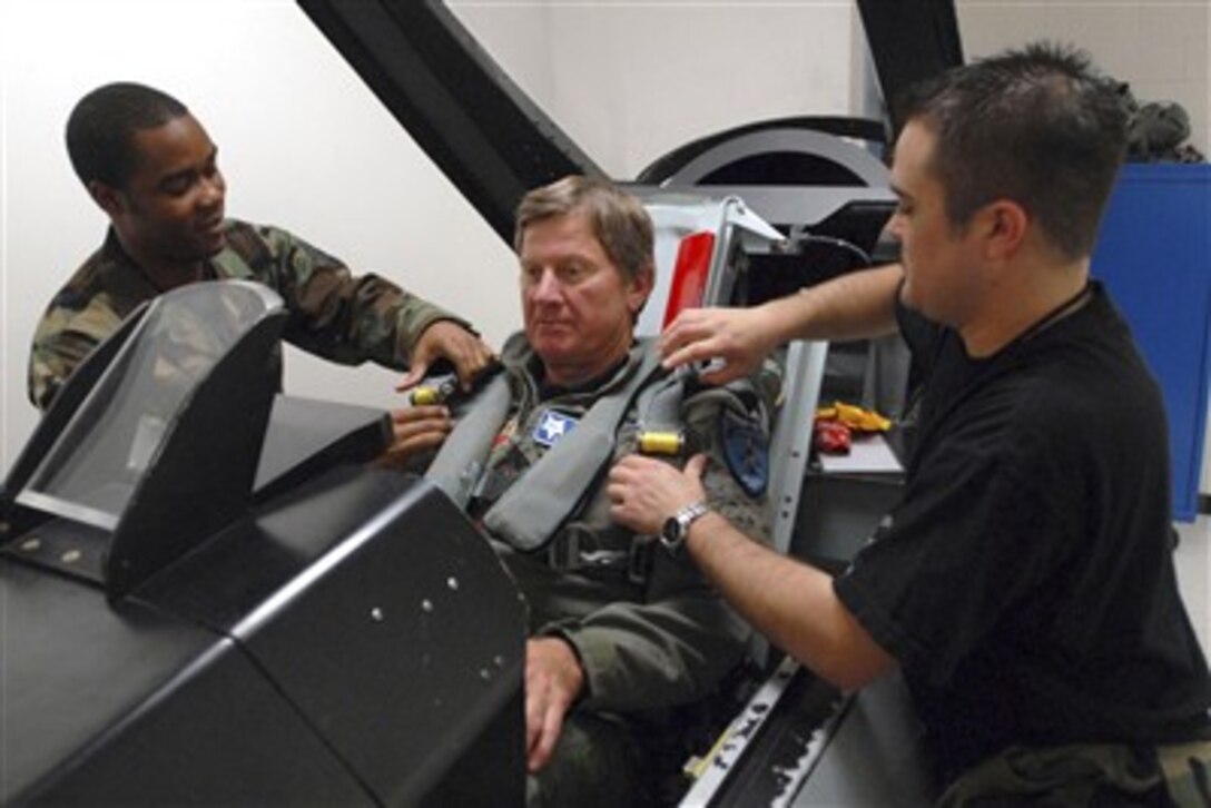 U.S. Air Force Tech. Sgt. Ahmad Clemmons, left, and Staff Sgt. Kyle Dyment strap Steve Spurrier, the head coach for University of South Carolina's football team, into a mockup of the cockpit in an F-16 Fighting Falcon aircraft before an orientation flight at McEntire Joint National Guard Base, S.C., March 8, 2007.