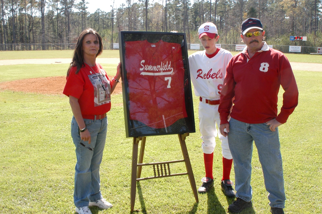 SUMMERFIELD, La. - Jill Pucket, Logan Bowman, and Jon Bowman, the family of Lance Cpl. Jon Eric Bowman, stand at the retirement ceremony of the fallen Marine's high school baseball jersey. Summerfield High School retired the jersey in recognition of Bowman's heroic contribution to the Marine Corps and their town.