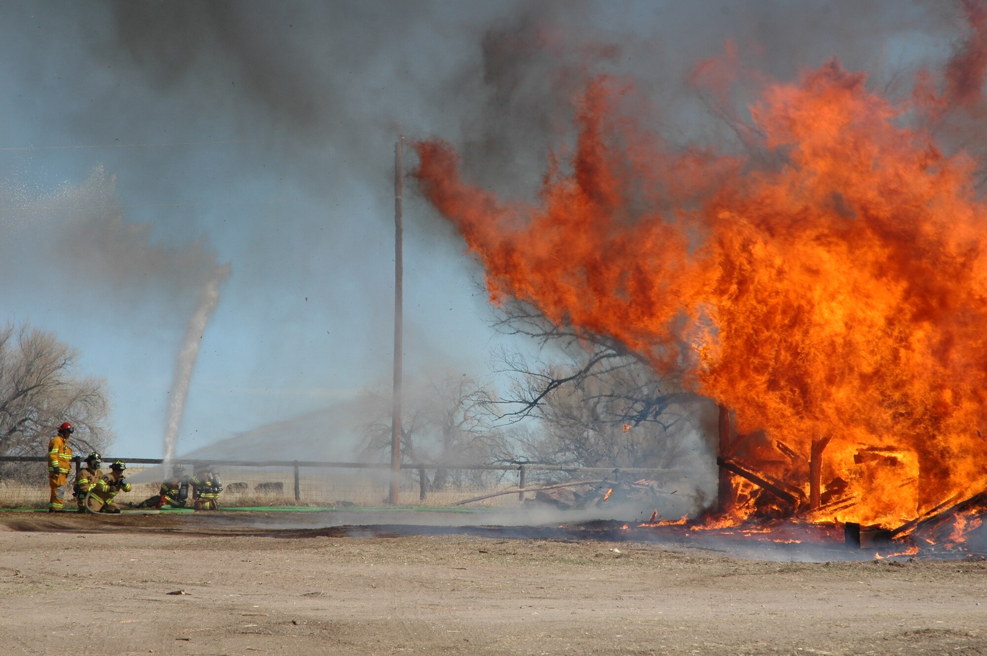 Peterson Air Force Base firefighters dowse flames coming at them during a joint training exercise March 19 at the Banning Lewis Ranch. “The building was going to be torn down and hauled away,” said Bill Ritchie, ranch project manager. “We decided to offer it up to the Colorado Springs Fire Department for training and they took it from there. In this case, we helped each other out.” (U.S. Air Force photo by Tech. Sgt. Matt Gilreath)