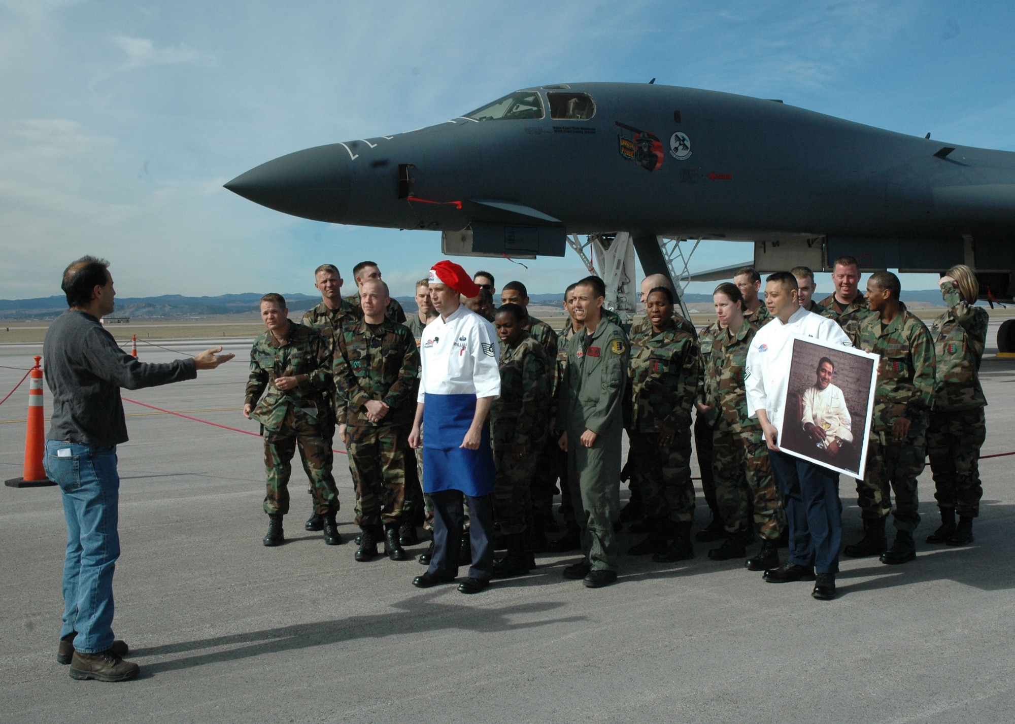 Alan Madison, Emeril Live producer, briefs a crowd of Ellsworth's Airmen in front of a B-1 to film an opening shot for the Emeril Live show. On Mr. Madison's cue, Tech. Sgt. Wesley Williams, dining facility manager here and winner of the Emeril Live military chef contest, challenged Emeril to successfully copy his recipe. After Sergeant Williams threw down the culinary gauntlet, the group of Airmen let out a resounding BAM across Ellsworth’s flightline.