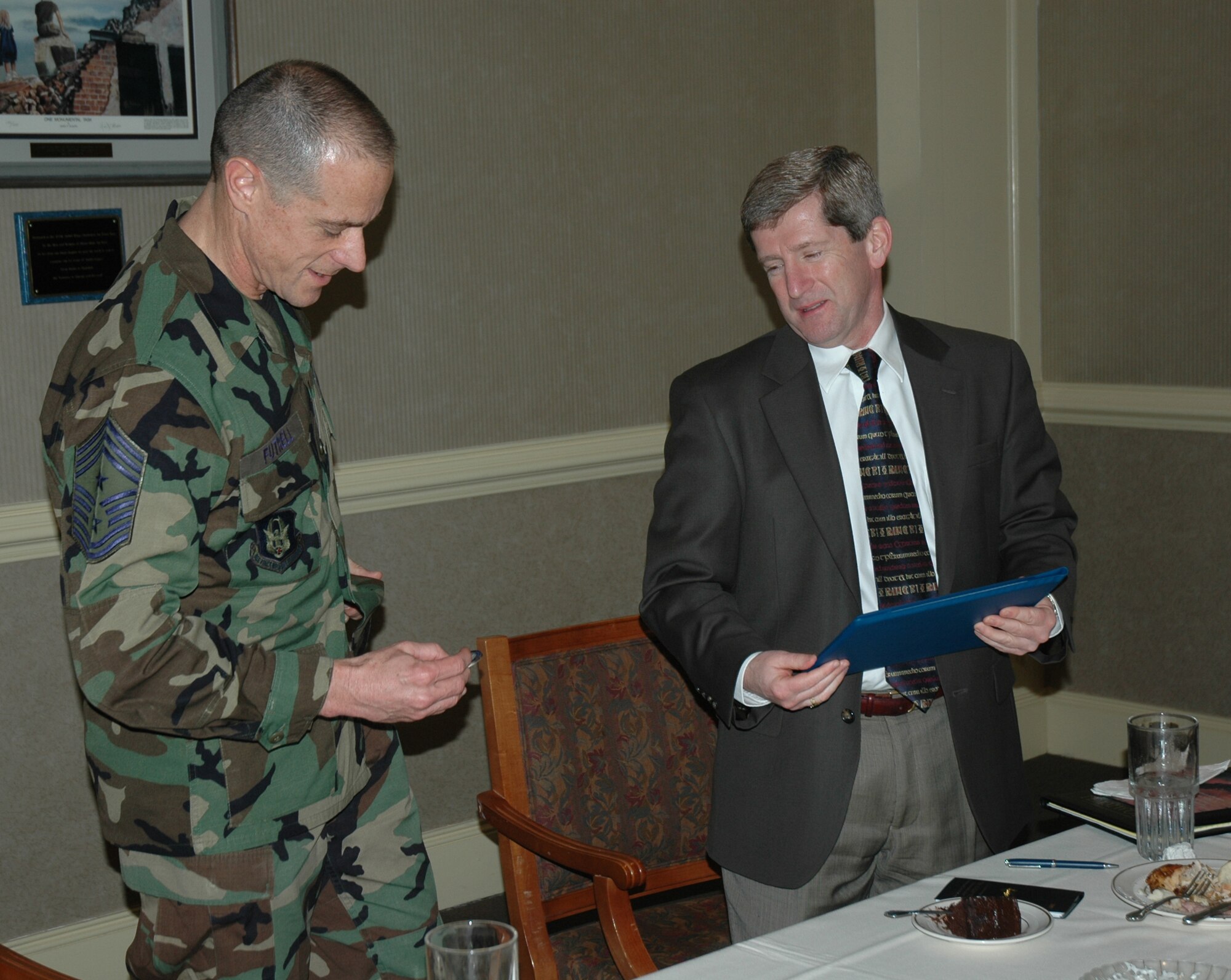 Chief Master Sgt. Ben Futrell, command chief master sergeant for the 315th Airlift Wing, Charleston Air Force Base, S.C., presents Bill Maher a coin during the honorary commanders luncheon. (photo by Capt. Wayne Capps, USAFR)