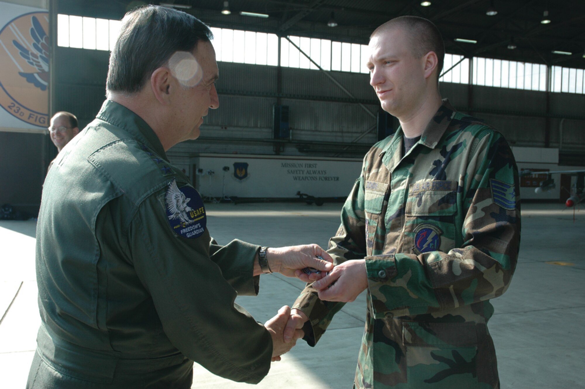 SPANGDAHLEM AIR BASE, Germany -- Gen. Tom Hobbins, U.S. Air Forces in Europe commander, coins Tech. Sgt. Michael Dickon, 52nd Logistics Readiness Squadron, while at Spangdahlem Air Base to shoot an American Forces Network commercial here March 15.  