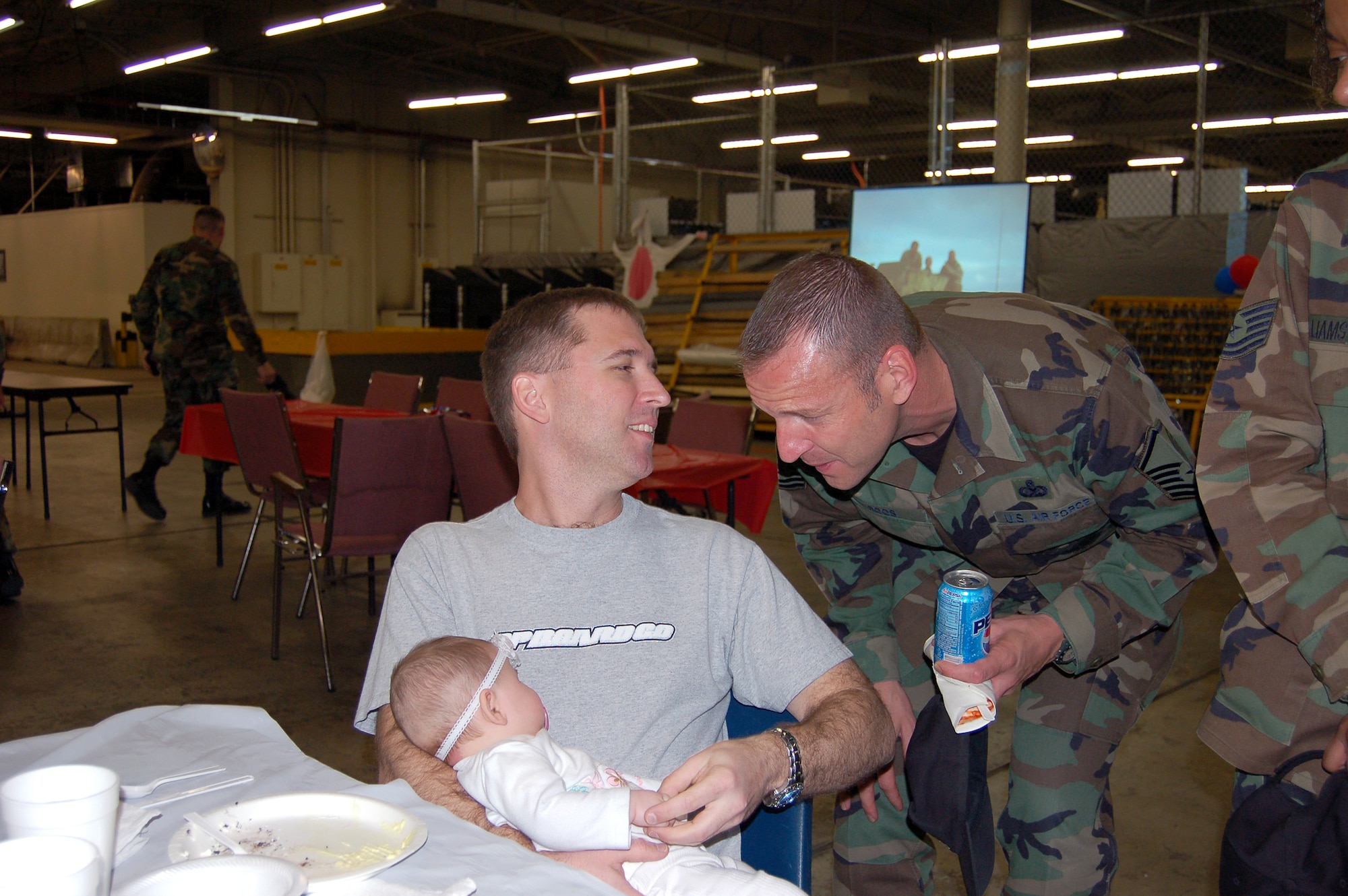 Master Sgt. Jason Fisk holds his six-month-old daughter Amelia, whom he met for the first time upon his return from deployment, while talking with Master Sgt. Michael Roos at the Warrior Welcome at Hill Air Force Base, Utah, March 15. Both are assigned to the 75th Logistics Readiness Squadron. (U.S. Air Force photo)