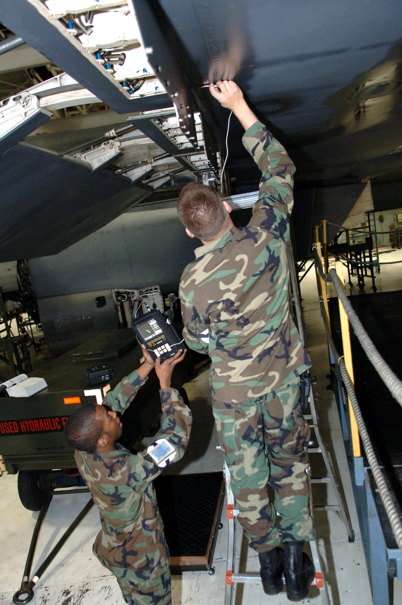 Airman 1st Class Ehud Torres and Senior Airman Raunedrick Nash inspect for possible cracks with the Nortec 2000D on the B-1B Lancer March 19 at Ellsworth Air Force Base, S.D. The Airmen are nondestructive inspections technicians with the 28th Maintenance Squadron.(U.S. Air Force photo/Airman 1st Class Angela Ruiz)