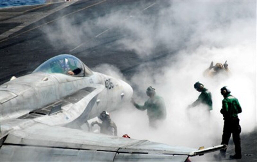 Steam from the steam-powered catapult of the aircraft carrier USS John C. Stennis (CVN 74) surrounds flight deck crewman and an F/A-18C Hornet aircraft as they prepare to launch the aircraft in the North Arabian Sea on March 16, 2007.  The John C. Stennis Carrier Strike Group is deployed in support of maritime security operations in the area.  