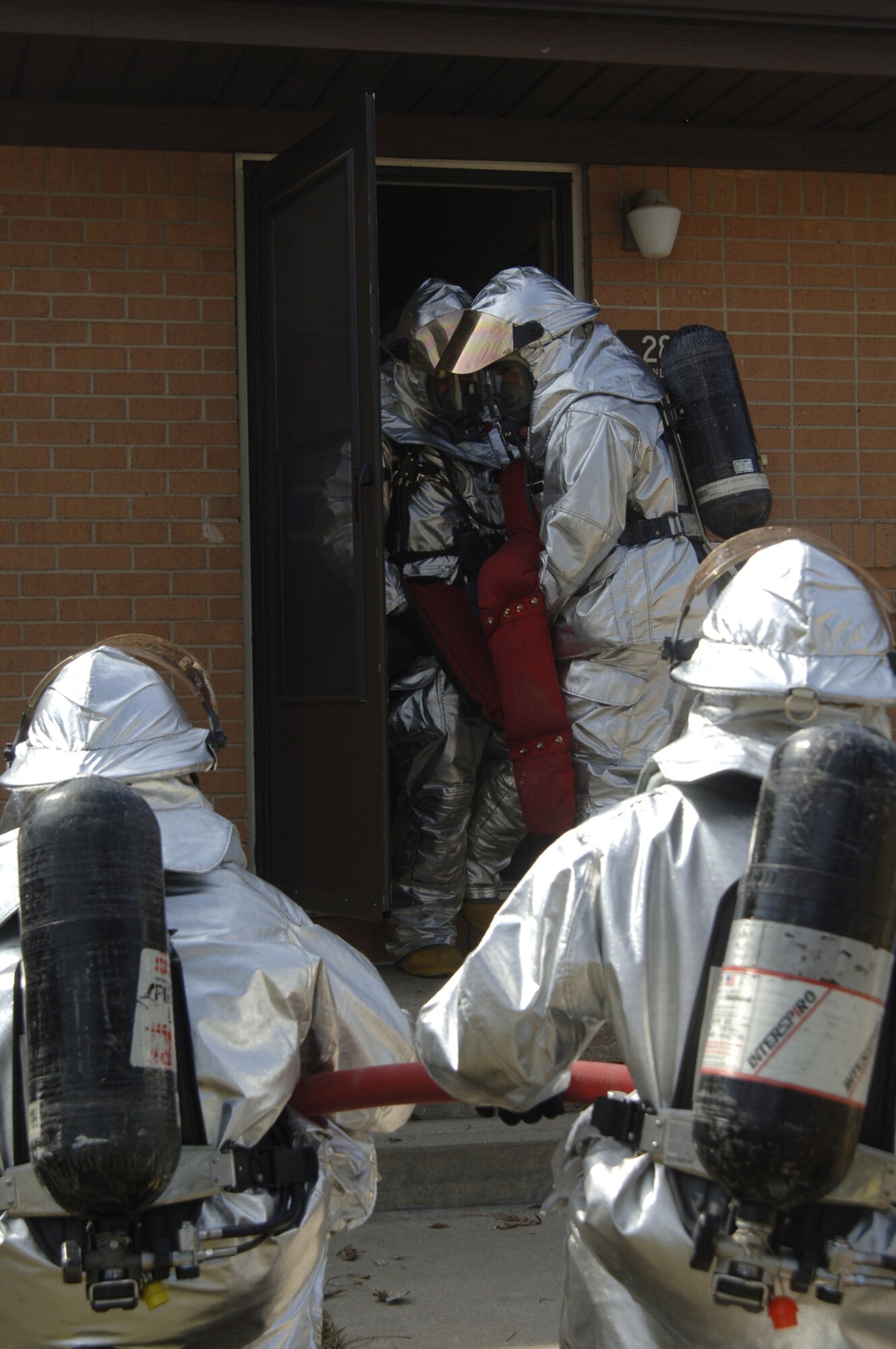 Firefighters from the 22nd Civil Engineer Squadron simulate carrying a body out of a burning building at McConnell March 13 during a tornado response exercise. During the exercise, McConnell's exercise evaluation team primarily assessed the effectiveness of the base's emergency notification systems. The EET also evaluated Team McConnell members' ability to shelter-in-place and each unit's capability to account for its members in an emergency situation. (Air Force photo by Airman 1st Class Roy Lynch)