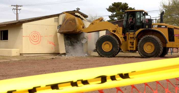 Col. Michael Bartley, 99th Air Base Wing commander, Nellis Air Force Base, Nev., drives the bulldozer that demolished the first home March 20, 2007, to make way for modern houses for military families.  (U.S Air Force photo by Senior Airman Larry E. Reid Jr.)
