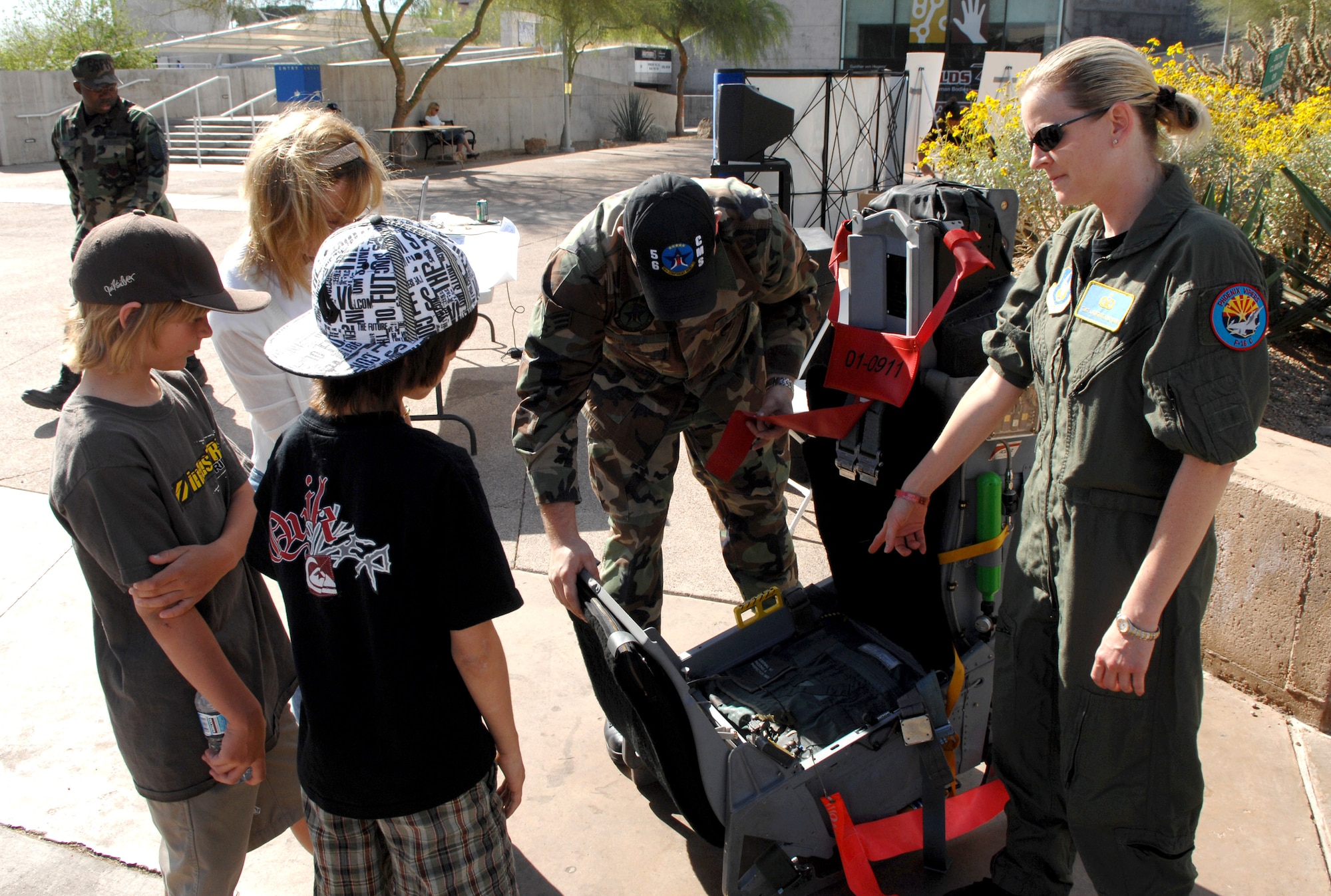 Senior Airman Rex Hicks (left) and Tech. Sgt. Erin Buchanan demonstrate an ejection seat outside the Arizona Science Center in downtown Phoenix during Air Force Week.  Sergeant Buchanan is with the 302nd Fighter Squadron and Airman Hicks is with the 56th Component Maintenance Squadron at nearby Luke Air Force Base. (U.S. Air Force photo/Staff Sgt. Brian Ferguson)
