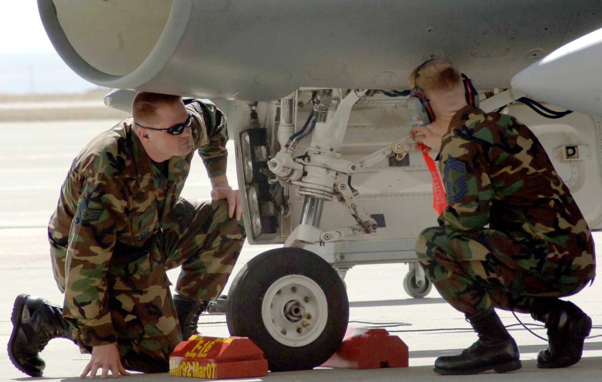 MOUNTAIN HOME AIR FORCE BASE, Idaho -- Staff Sgt. David Lang, a dedicated crew chief with the 389th Aircraft Maintenance Unit, and Chief Master Sgt. William Harner Jr., 366th Operations Group enlisted manager, lock safety pins into the landing gear of an F-16CJ during the 389th Fighter Squadron’s “fini flight” ceremony here March 16. The squadron’s last five F-16s permanently leave the base March 29 as part of the 366th Fighter Wing’s move to a core F-15E unit. Air Force photo by Master Sgt. Dave Wheeler