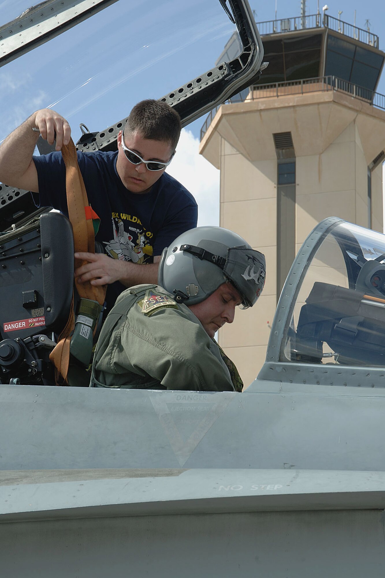 Private (Pte) Francois Brisson, a crew chief from Montreal, Quebec, straps Capt. James Kettle into his Canadian Forces CF-18 Feb. 22 at Homestead Air Reserve Base, Fla. The three-week exercise pitted Canadian CF-18s against F-16s from Homestead’s 93rd Fighter Squadron. Also, Canadian fighter pilot students participated in the annual exercise for the first time in its history. (Canadian Air Force photo/Cpl. J.A. Wilson)
