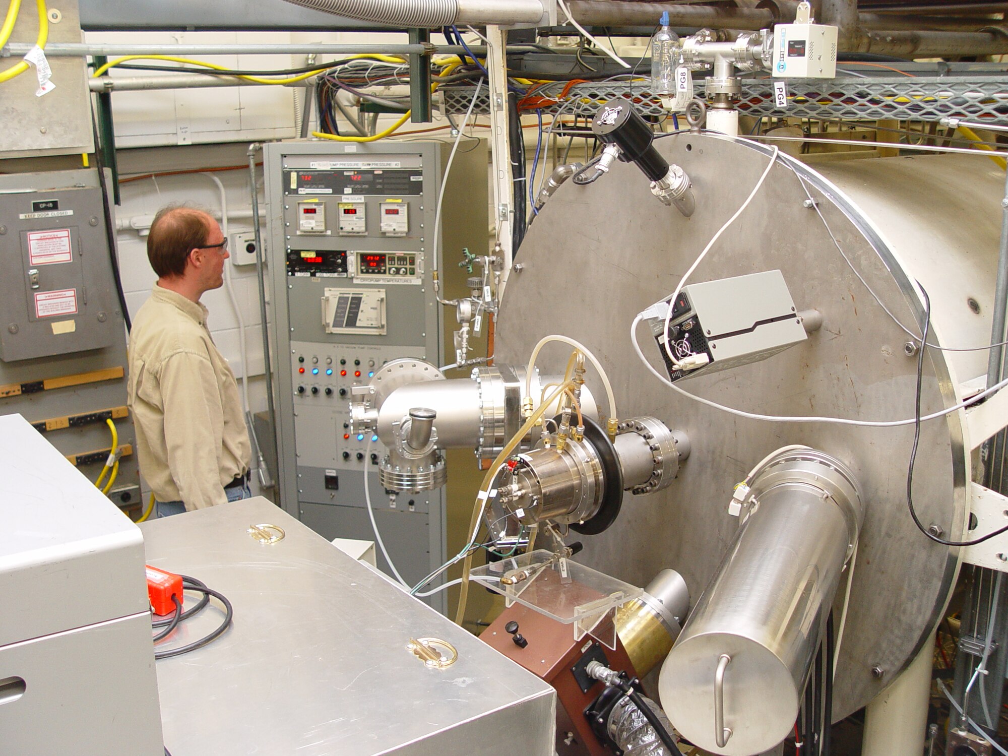 Danny Crews, systems engineer for instrumentation and controls at the Space Chambers research lab, checks pressure readings on the pumping system control rack to the left of the CCOSE Chamber. (Photo by Philip Lorenz III)