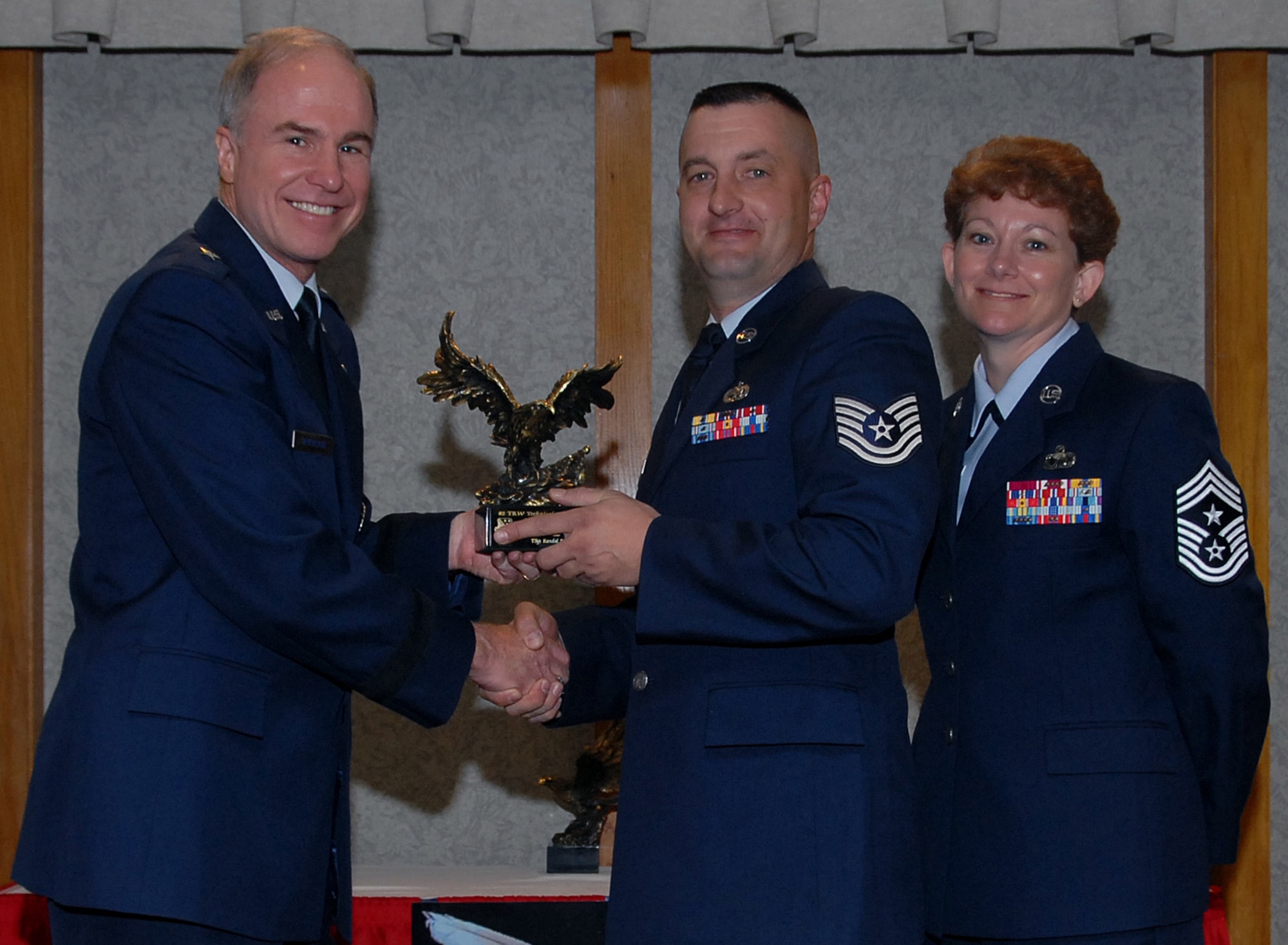 Tech. Sgt. Randal Pionek of the 982nd Training Group accepts the 82nd Training Wing NCO Instructor of the Year award March 19 from 82nd TRW Commander Brig. Gen. Richard Devereaux and 82nd TRW Command Chief Chief Master Sgt. Jeannie McLean. Sergeant Pionek was cited for finding and repairing a bent pin on an engine fuel control sequencing valve, saving $75,000, developing an engine equipment tooling inventory log and coached six at-risk students in the Clark County education program. (U.S. Air Force photo/Mike Litteken)