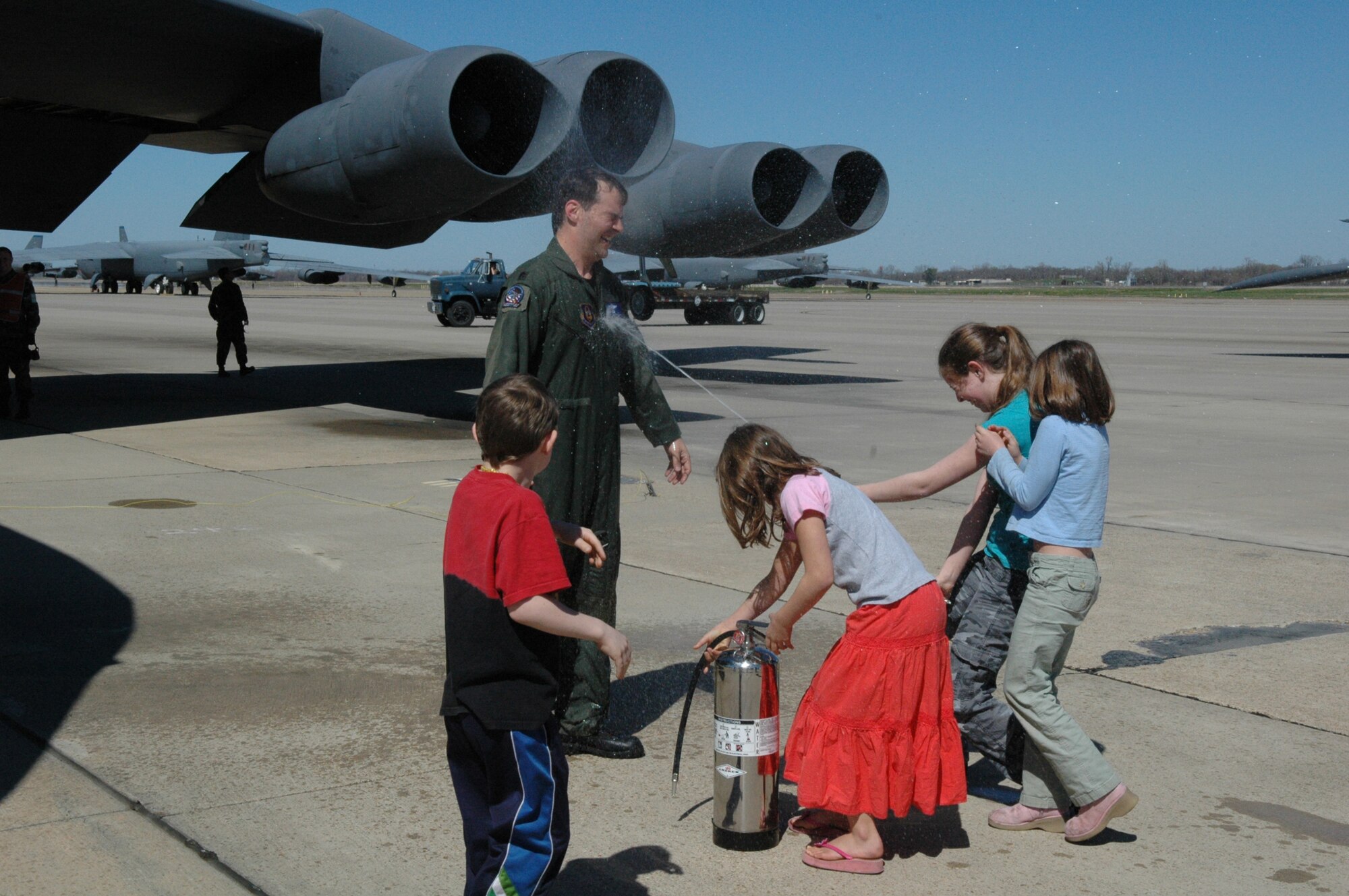 Daughter Katherine (far right) sprays dad, Lt. Col. Paul Harper, 93rd Bomb Squadron B-52 instructor aircraft commander, as he completes his fini-flight on a bomber Sunday, March 4. Also pictured are (from left to right): son, Stephen , and daughters, Megan and Rebecca. (U.S. Air Force photo/Tech. Sgt. Jeff Walston)