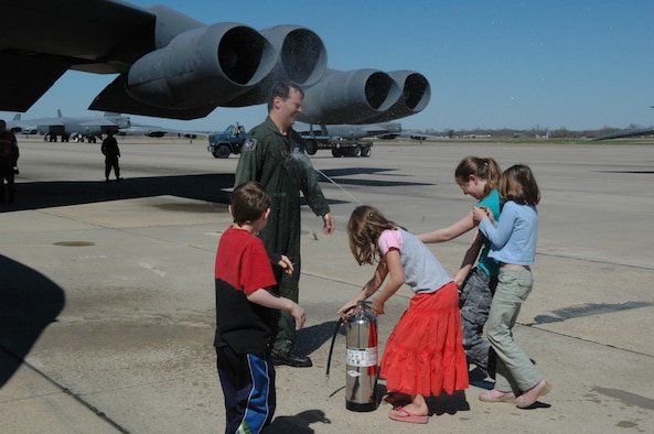 Daughter Katherine (far right) sprays dad, Lt. Col. Paul Harper, 93rd Bomb Squadron B-52 instructor aircraft commander, as he completes his fini-flight on a bomber Sunday, March 4. Also pictured are (from left to right): son, Stephen , and daughters, Megan and Rebecca. (U.S. Air Force photo/Tech. Sgt. Jeff Walston)