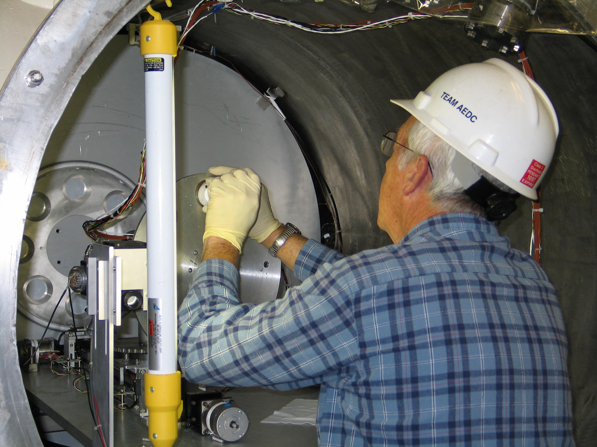ATA Outside Machinist Mitch Christian installs the white thermal control paint sample from the Air Force Research Laboratory into AEDC’s newly configured Characterization of Combined Orbital Surface Effects Chamber prior to the system checkout last December. (Photo by John Prebola)