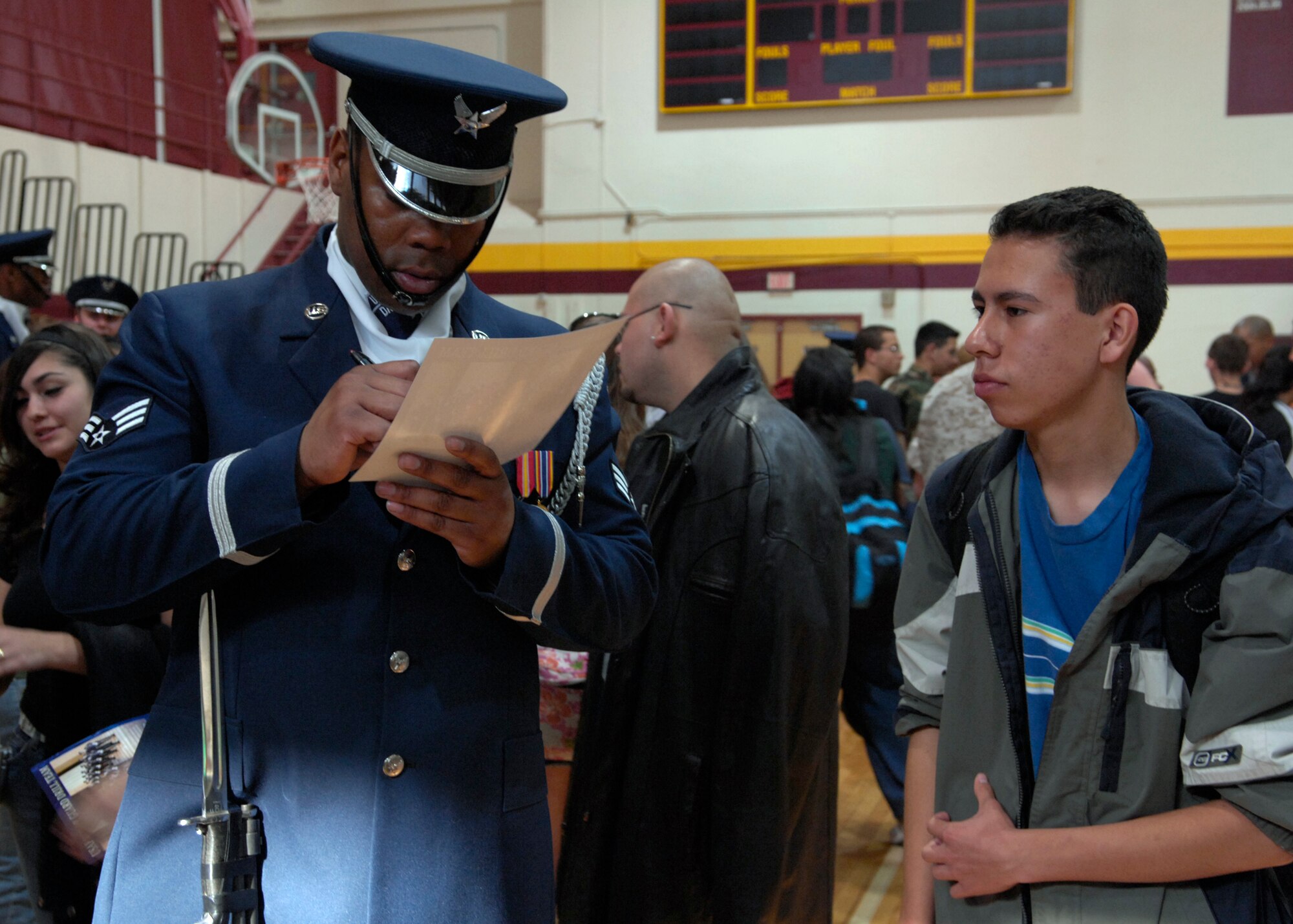 Senior Airman Isaac Kendrick of the United States Air Force Honor Guard Drill Team, signs autographs AF recruiting posters after the team performance at Valley High School, Albuquerque, N.M., March 16, 2007. The Drill Team is the traveling component of the Air Force Honor Guard and tours Air Force bases world wide showcasing the precision of today's Air Force to recruit, retain, and inspire Airmen for the Air Force mission. (U.S. Air Force photo by Airman 1st Class Rusti Caraker)(Released)