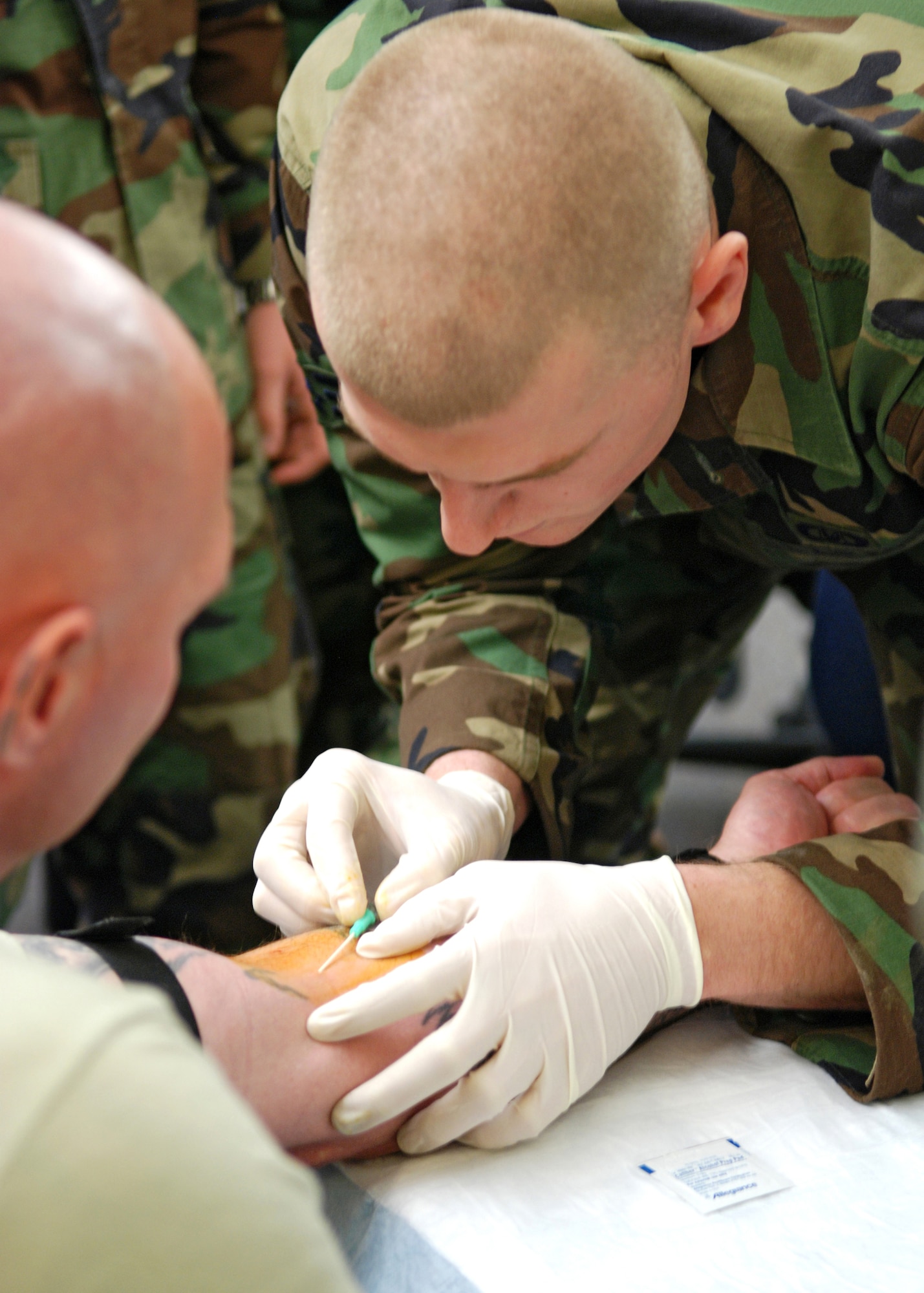 Senior Airman Tyler Harrington, a 22nd Training Squadron SERE specialist, practices the insertion of intravenous fluids into the arm of Army Staff Sgt. Patrick Kling, a drill sergeant and combat lifesaver course instructor. (U.S. Air Force photo/Airman 1st Class Kali L. Gradishar)