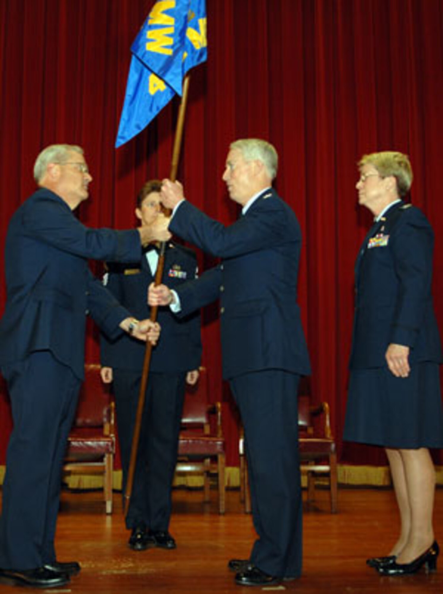 Brig. Gen. James L. Melin, 452d Air Mobiltiy Wing commander, left, hands the medical group guidon to the new 452d Medical Group commander Col. Raymond M. Butler, center, while former commander Col Janice McKibban looks on.  (U.S. Air Force photo by 4th Combat Camera Squadron)
