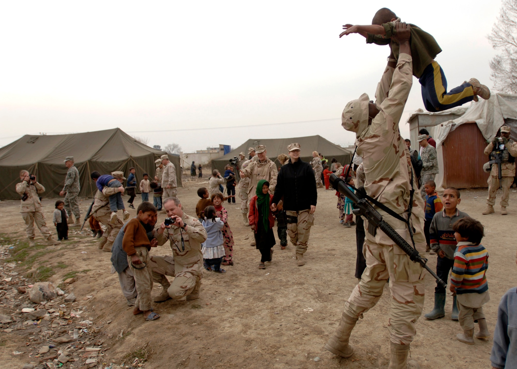 Department of Defense civilians and coalition servicemembers play with local refugee children March 16 in Dar Ul Aman in support of the volunteer community reach program. During the visit, some 200 bags of clothes, shoes and toys were distributed.  The program volunteers provide this service every month thanks to donated items from U.S. citizens.  (U.S. Air Force photo/Tech. Sgt. Cecilio M. Ricardo Jr.) 