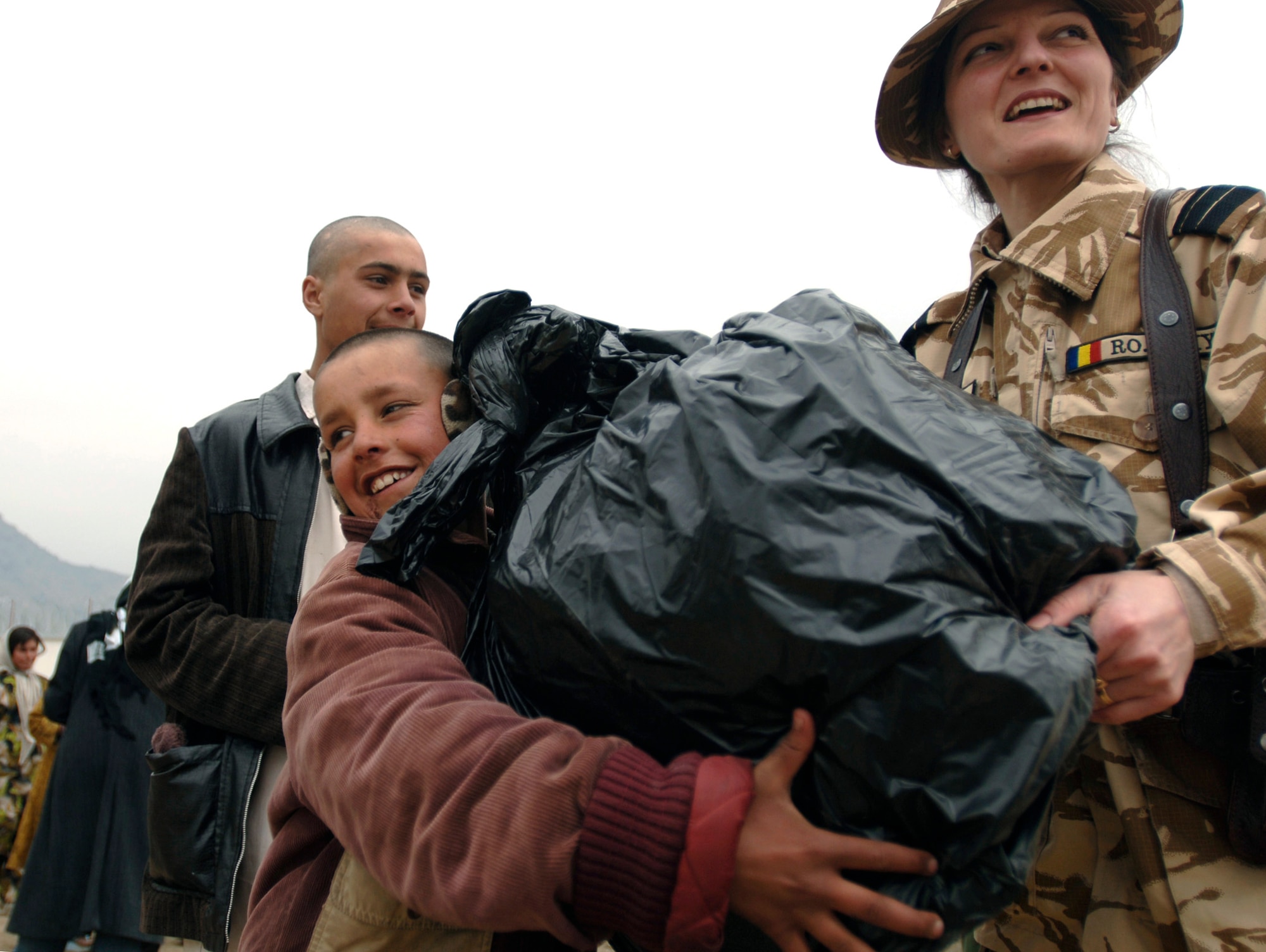Romanian Sergeant 1st Class Maria Jamed gives a bag of clothes, shoes and toys to a local refugee child in Dar Ul Aman in support of the volunteer community reach program March 16. During the visit, some 200 bags of supplies were distributed successfully to 200 families. The program volunteers provide this service every month thanks to donated items from U.S. citizens.  (U.S. Air Force photo/Tech. Sgt. Cecilio M. Ricardo Jr.) 