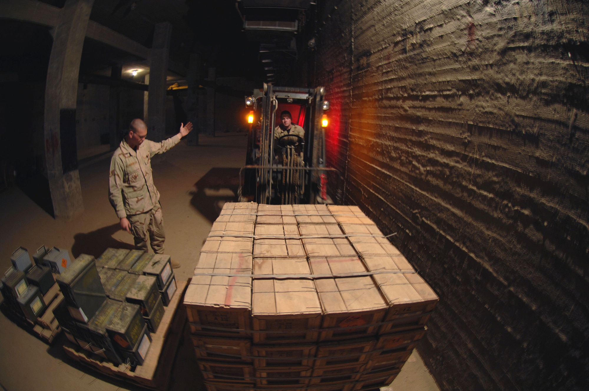 Staff Sgt. Michael Bigelow guides Staff Sgt. Trevor Ryan toward a pallet of ammunition inside an earth-covered munitions storage facility March 21 at Kirkuk Air Base, Iraq.  The ammo is used by expeditionary security forces Airmen to provide security to the base. The Airmen are munitions specialists with the 506th Air Expeditionary Group.  (U.S. Air Force photo/Senior Airman Bradley A. Lail)
