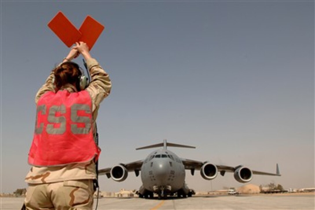 A U.S. Air Force airman directs the pilots of a C-17 Globemaster III aircraft carrying cargo to a parking spot at Balad Air Base, Iraq, on March 14, 2007.  The 332nd Expeditionary Logistics Readiness Squadron receives 16-tons of inbound cargo monthly at the base.   