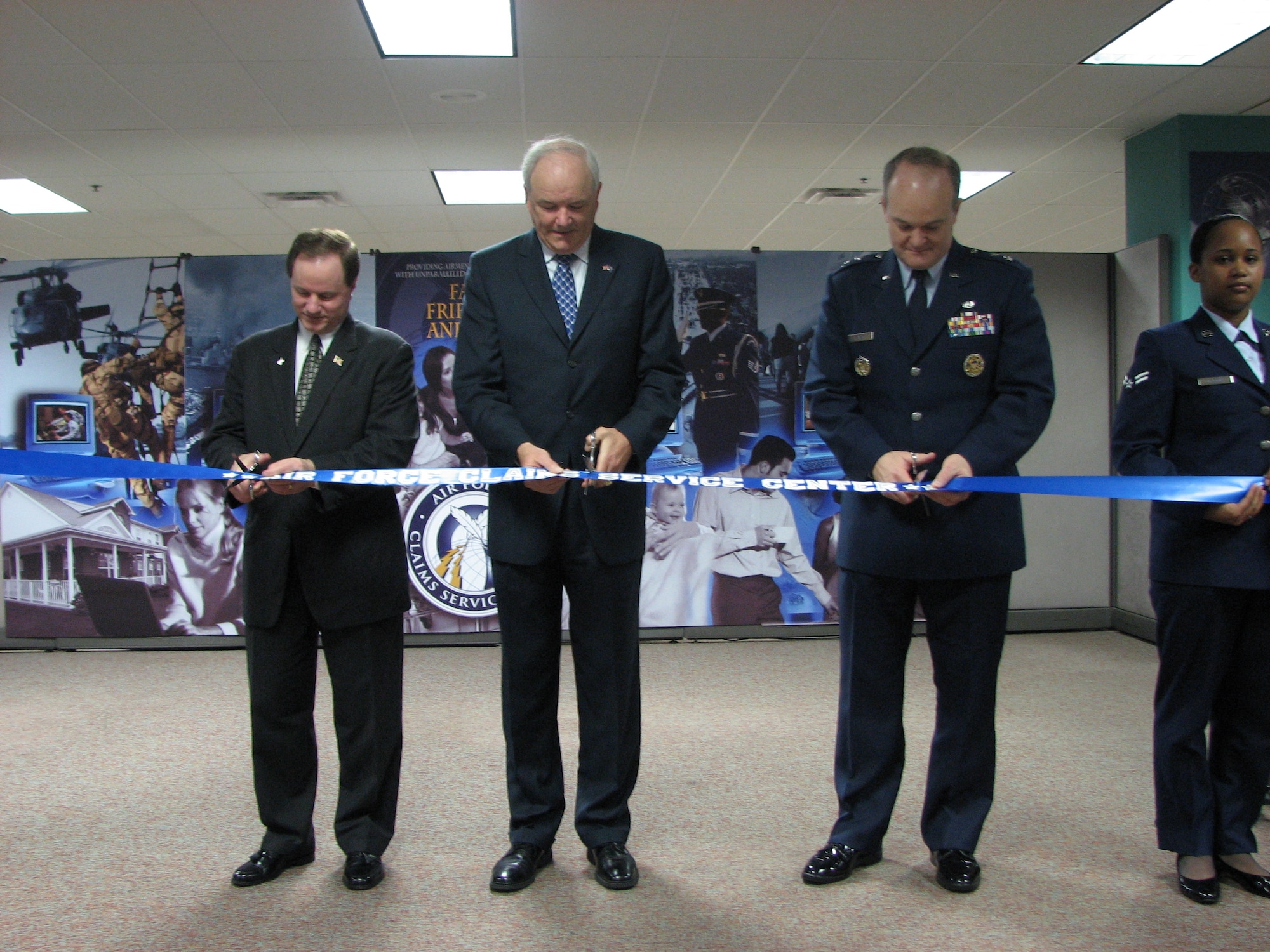 The Air Force transformed processing of personal property claims with the March 23 dedication of the new Air Force Claims Service Center in Kettering, Ohio. The single center now provides Air Force people worldwide with on-line claims filing and 24/7 toll-free, live personal assistance via telephone. Cutting the ribbon at the AFCSC from left to right is Zack Gaddy, Director of the Defense Finance and Accounting Service, Michael Wynne, Secretary of the Air Force and Maj. Gen. Jack Rives, Air Force Judge Advocate General.   Assisting them is Airman First Class Sherri Igartua of the AFCSC.  Air Force Photo by Tech. Sgt. Steve Moore.