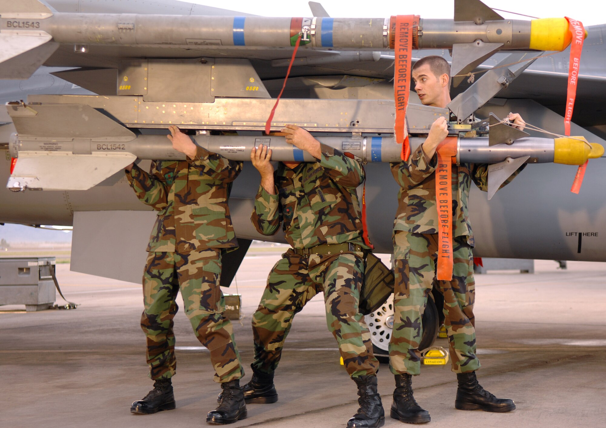 (From left) Senior Airman David Foster, Tech. Sgt. Greg Goodro and Staff Sgt. Cameron Linegar load an AIM-9 onto the wing of an F-16C Fighting Falcon during Good Morning Arizona, a morning show filmed at Luke Air Force Base, Ariz., March 22. The show featured demonstrations from different career fields throughout the Air Force and helped promote Air Force Week. (U.S. Air Force photo/Staff Sgt. Brian Ferguson)