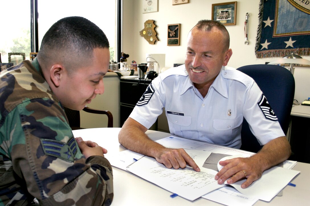 Master Sgt. Terry Swartz looks over paperwork with an Airman in his office. Sergeant Swartz was announced as one of the Air Mobility Command's 12 Outstanding Airmen March 12. (U.S. Air Force photo by 1st Lt. Lindsey Hahn)