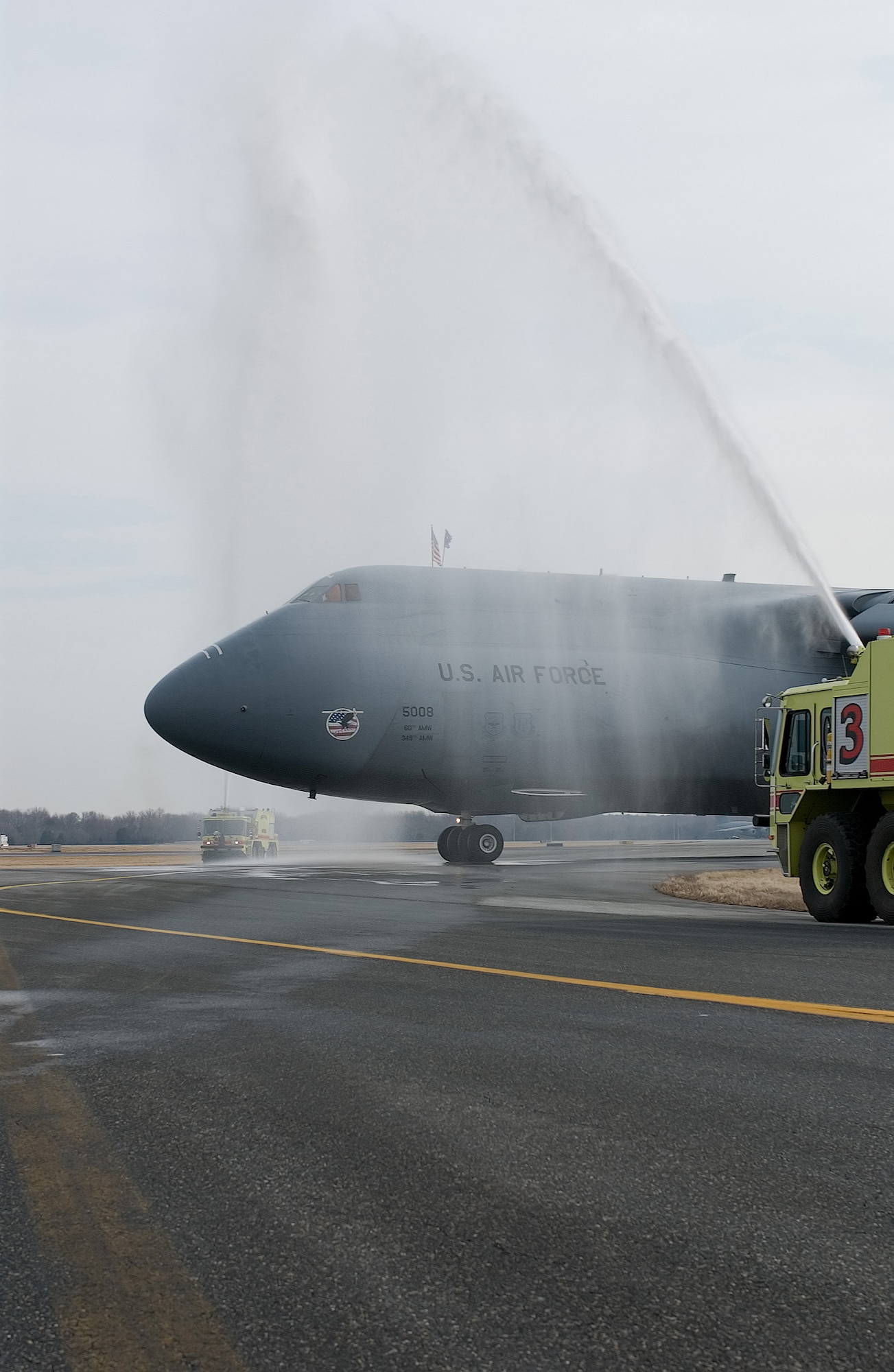 DOVER AIR FORCE BASE, Del. -- A C-5 Galaxy taxis through jets of water on the flightline here March 14, after an historic flight. The 3rd Airlift Squadron flew their final C-5 flight aboard the aircraft before taxiing between two fire trucks provided by the 436th Civil Engineer Squadron. The 3rd AS will begin flying C-17s later this year. (U.S. Air Force/Photo Roland Balik)