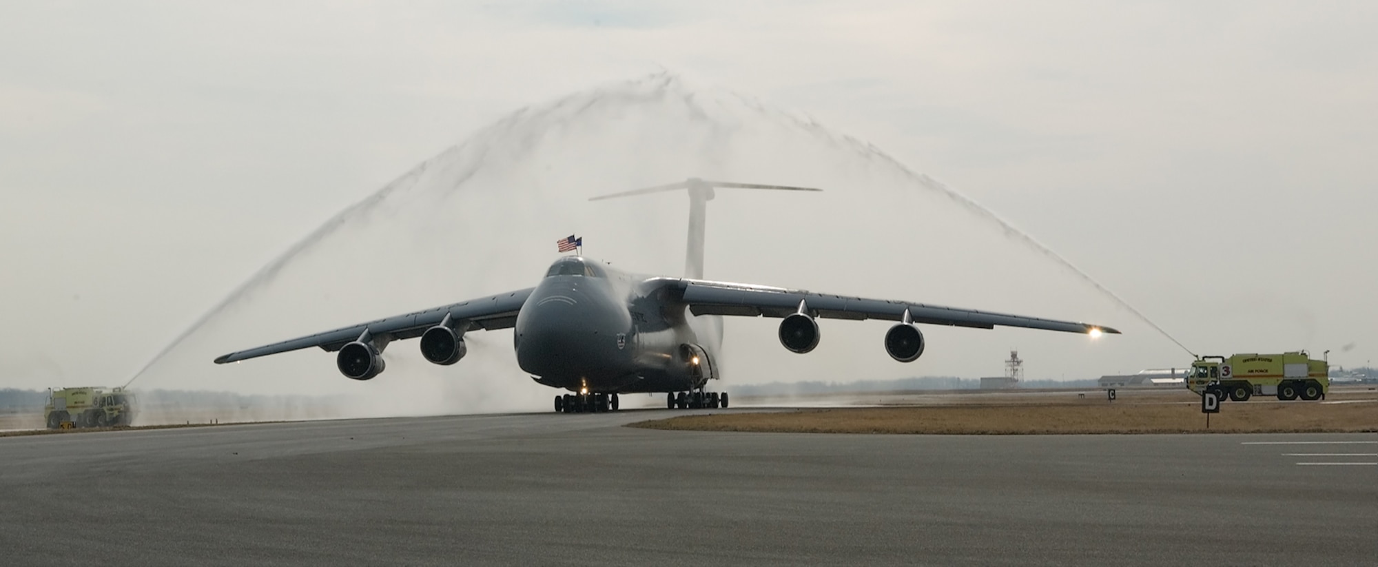 DOVER AIR FORCE BASE, Del. -- The 3rd Airlift Squadron’s final flight taxis through an arch of water provided by two 436th Civil Engineer Squadron fire trucks here March 14. (U.S. Air Force/photo Jason Minto)